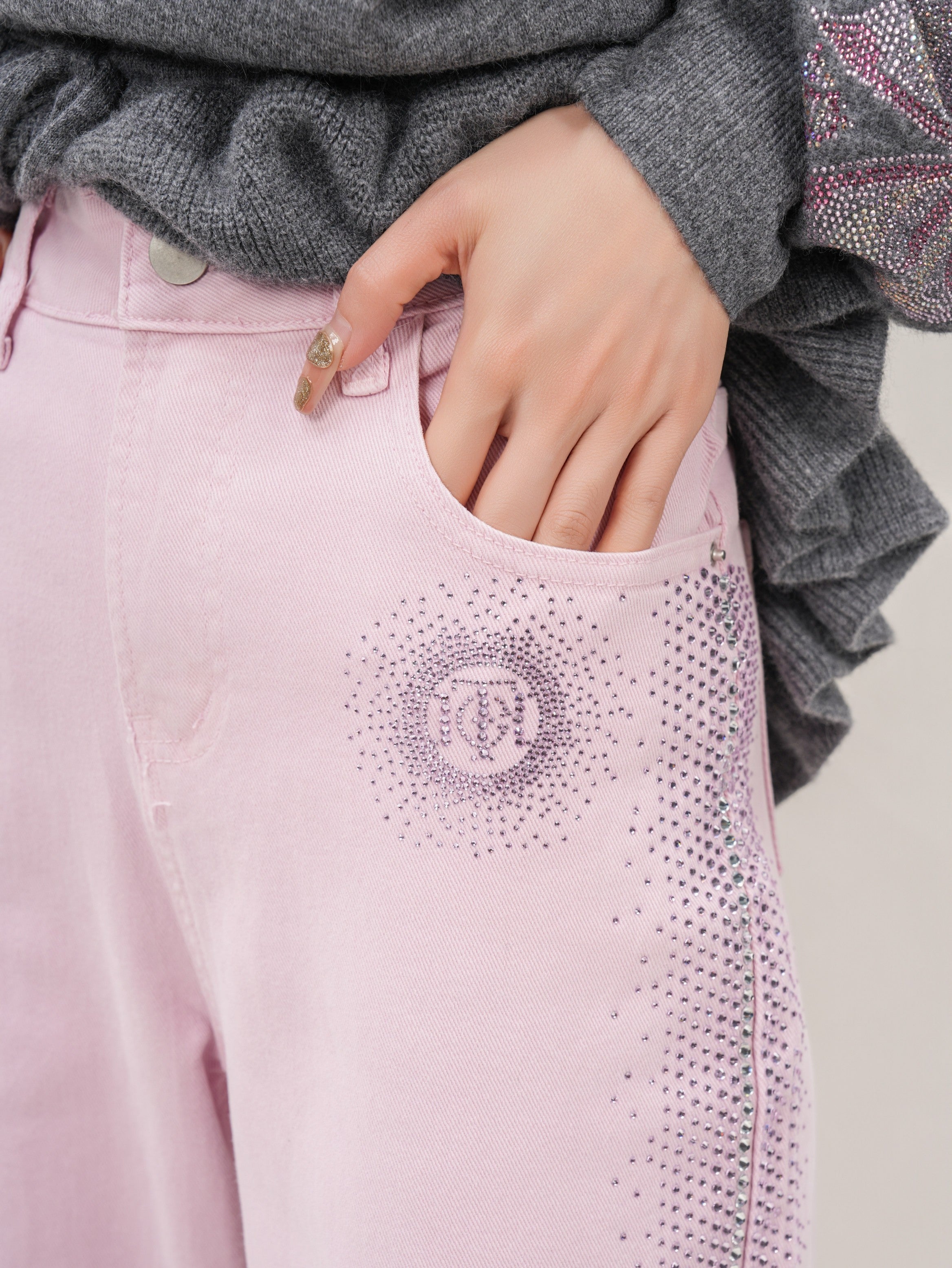 Pink pants with decorative elements worn by a person, focusing on the waist area. TCH Pink Rhinestone Gradient Denim Jeans with Logo Detail