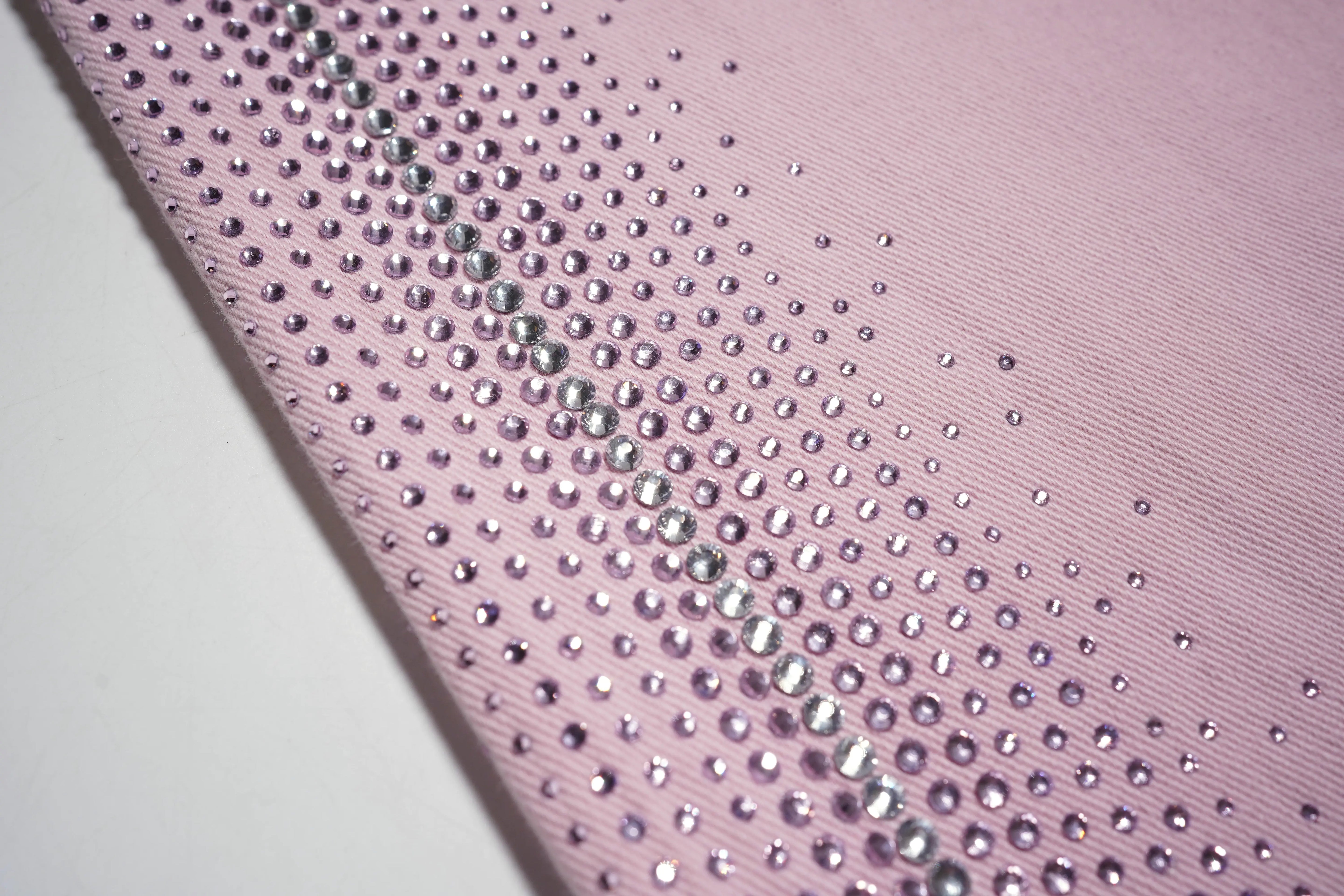 Close-up of a pink fabric with rhinestone embellishments, TCH Pink Rhinestone Gradient Denim Jeans with Logo Detail