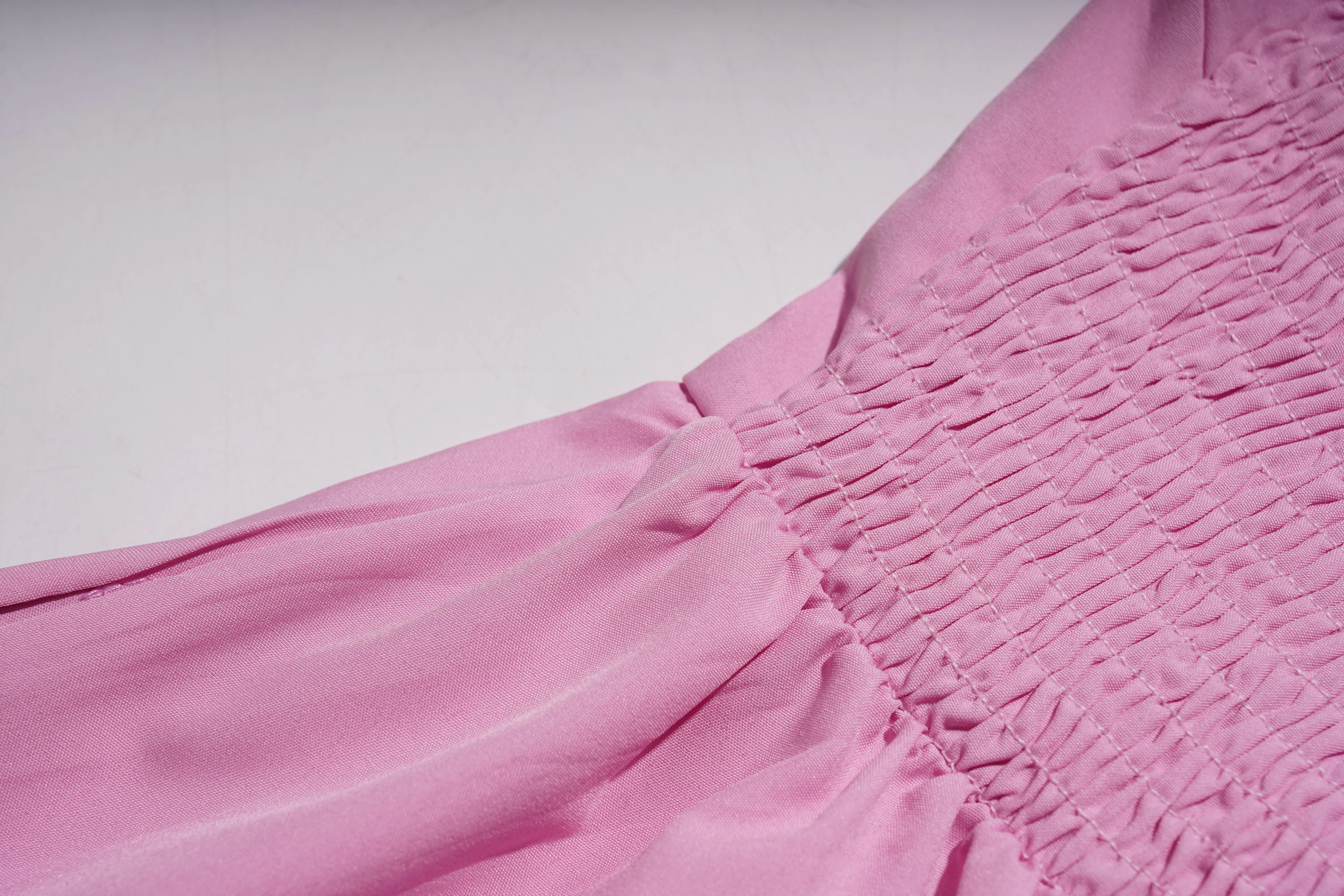 Close-up of pink fabric with smocked waistband on a light gray background, TCH Pink Rhinestone Teddy Laundry Story Dress