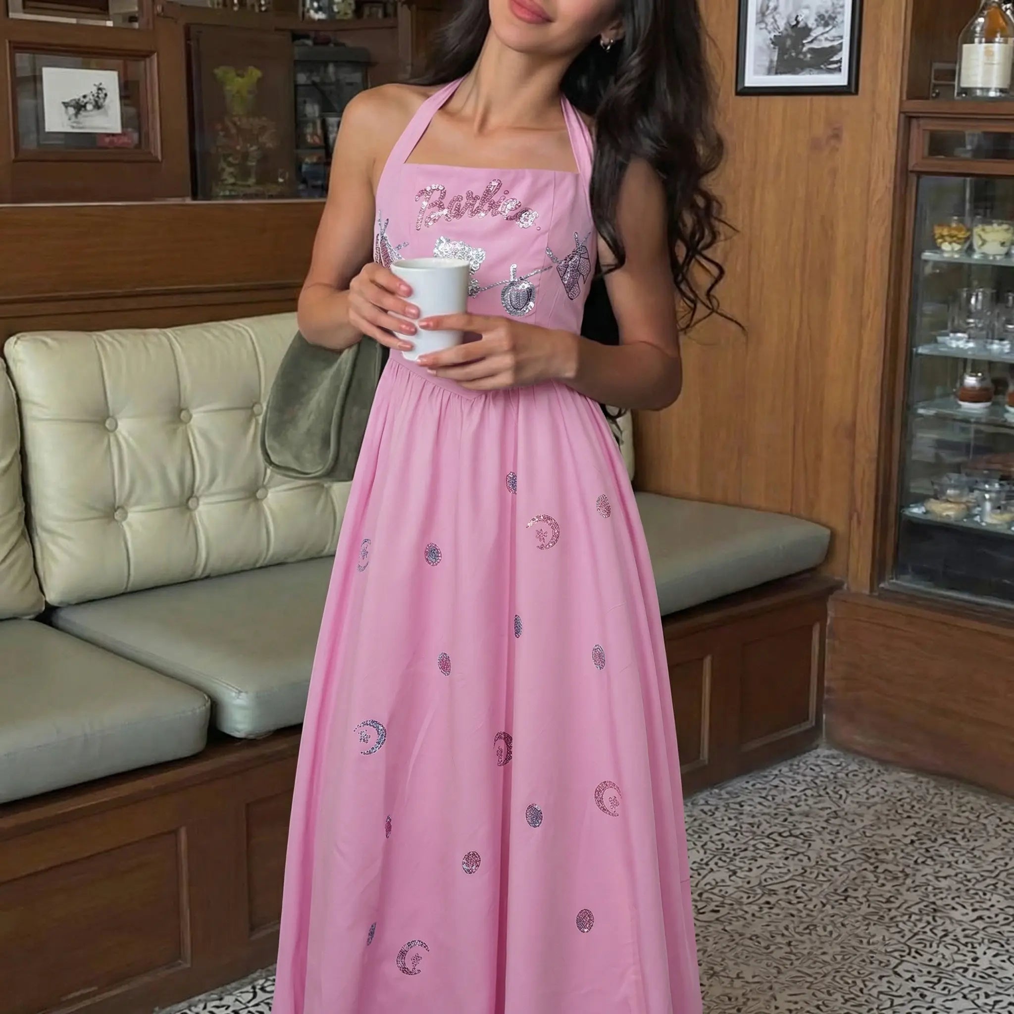 Woman in a pink dress holding a cup in a room with wooden furniture. TCH Pink Rhinestone Teddy Laundry Story Dress