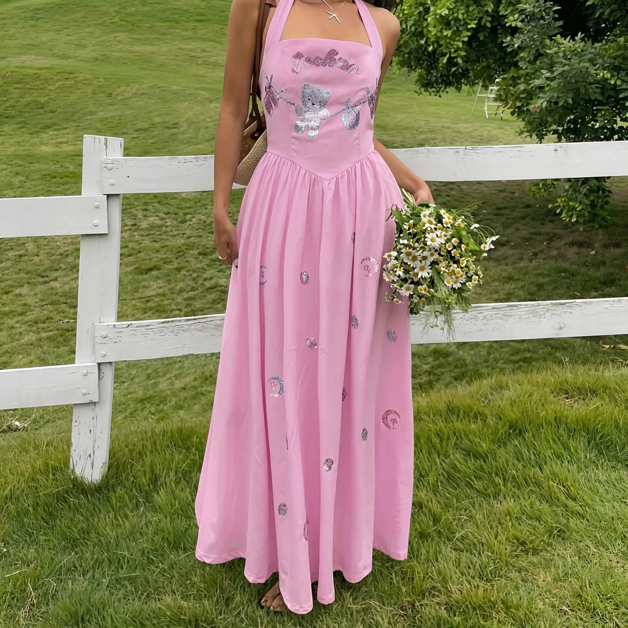 Person wearing a pink dress with floral patterns in a grassy outdoor setting. TCH Pink Rhinestone Teddy Laundry Story Dress