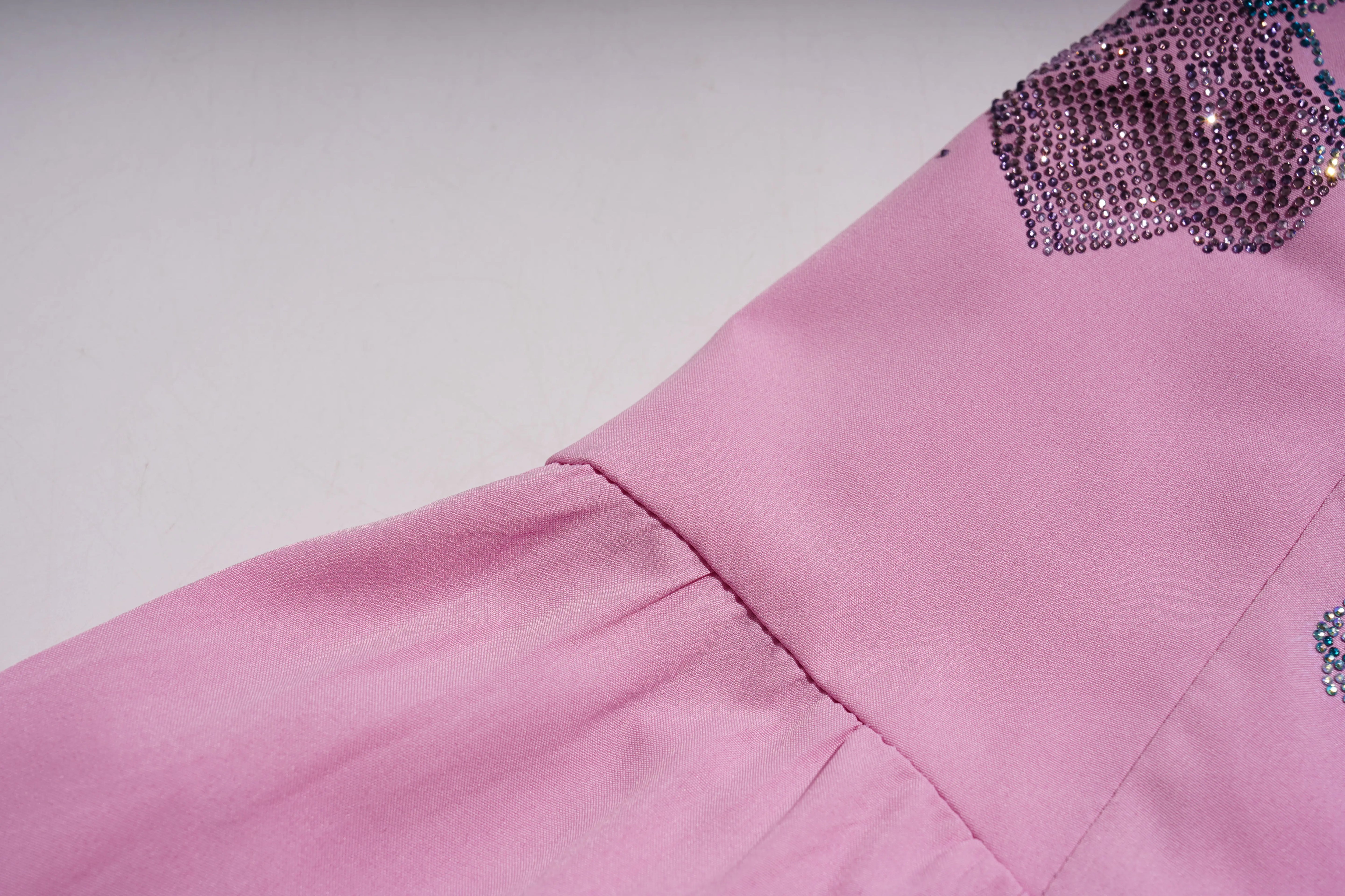 Close-up of a pink garment with decorative elements on a light gray background, TCH Pink Rhinestone Teddy Laundry Story Dress
