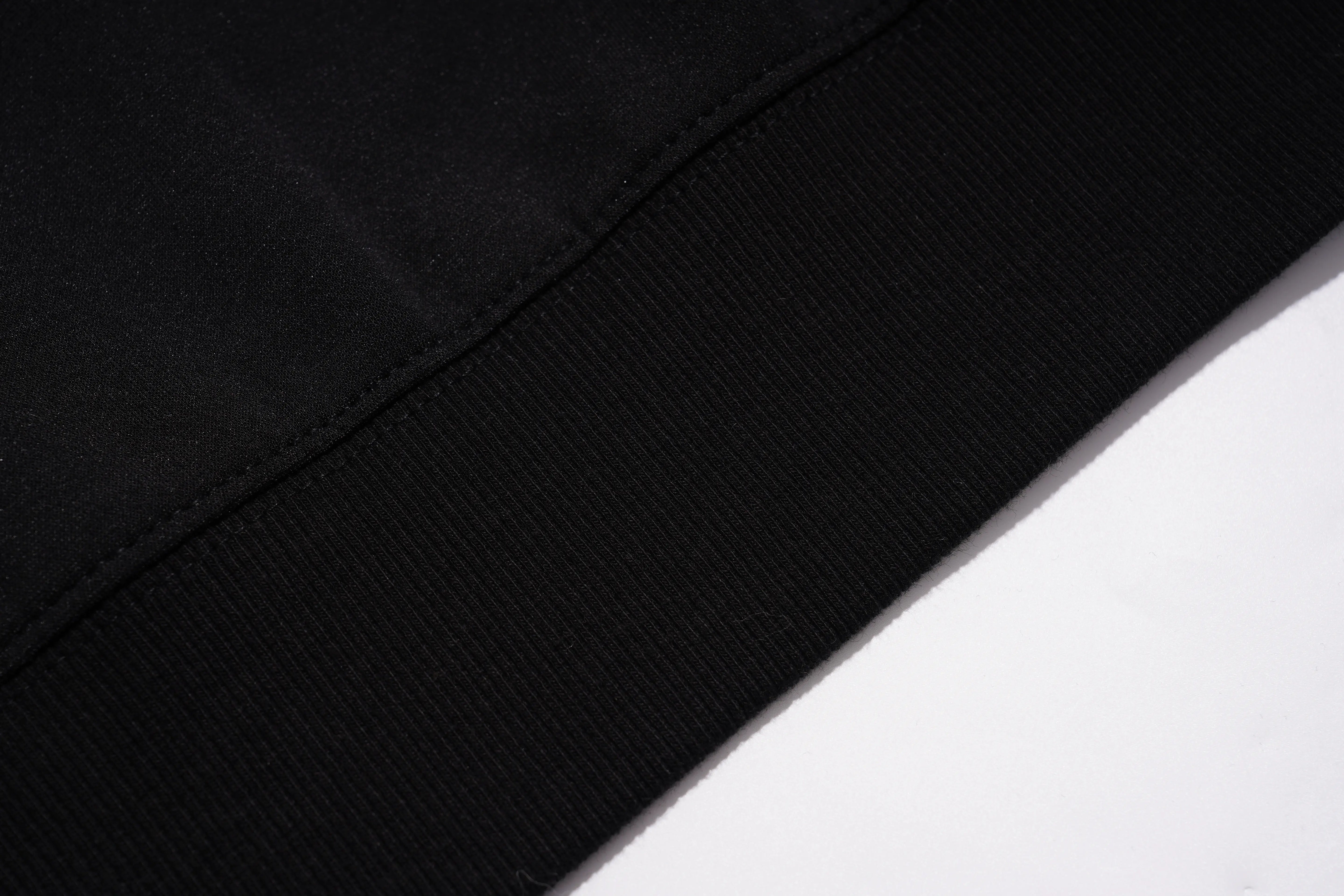 Close-up detail of a black ribbed knit cuff or hem with a clean white background visible in the lower right corner. TCH Pink Teddy Bear Rhinestone Graphic Black Sweatshirt
