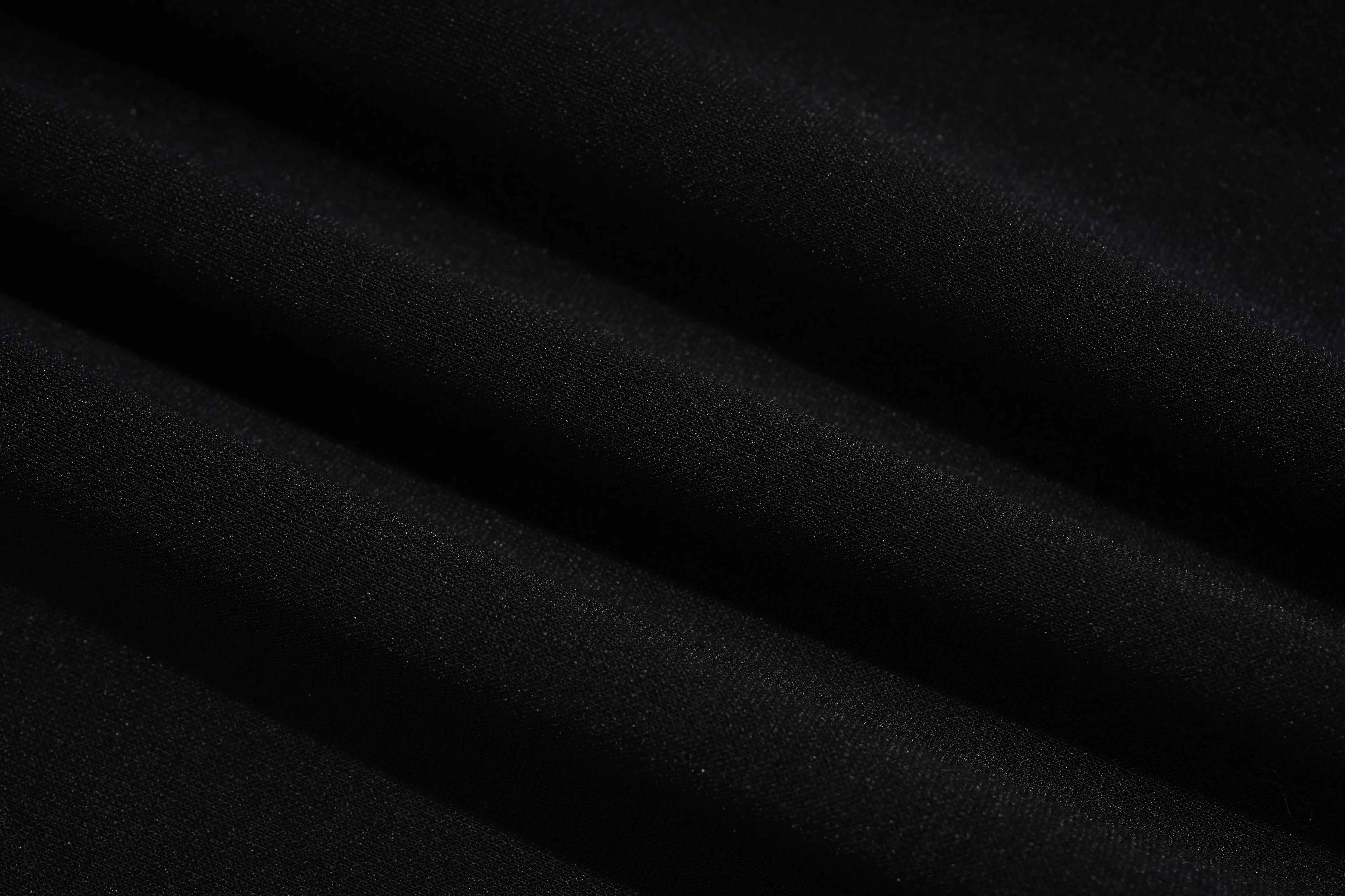 A close-up of draped black fabric with soft diagonal folds showing a subtle woven texture. TCH Pink Teddy Bear Rhinestone Graphic Black Sweatshirt