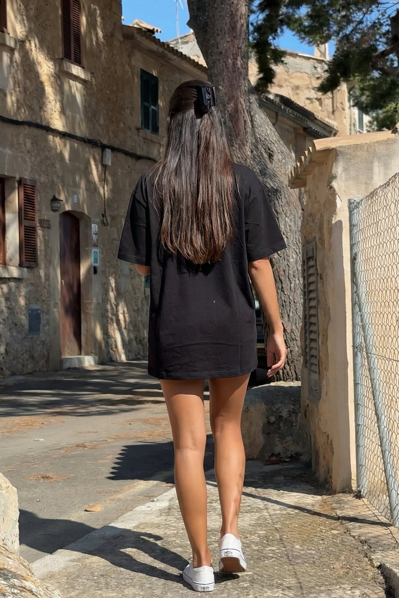 Person walking away on a sunlit street with stone buildings and trees. TCH Pink Teddy Bear Rhinestone T-Shirt