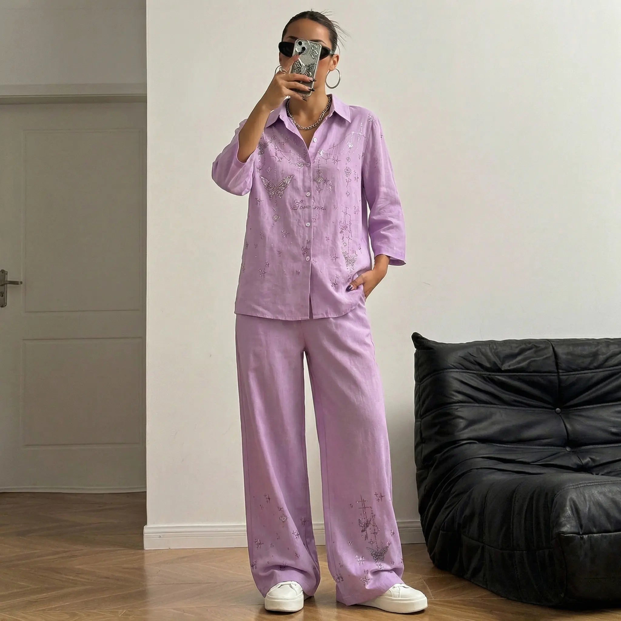 Person wearing a pink pajama set taking a mirror selfie in a room with a black bean bag chair. TCH Purple Rhinestone Butterfly Set