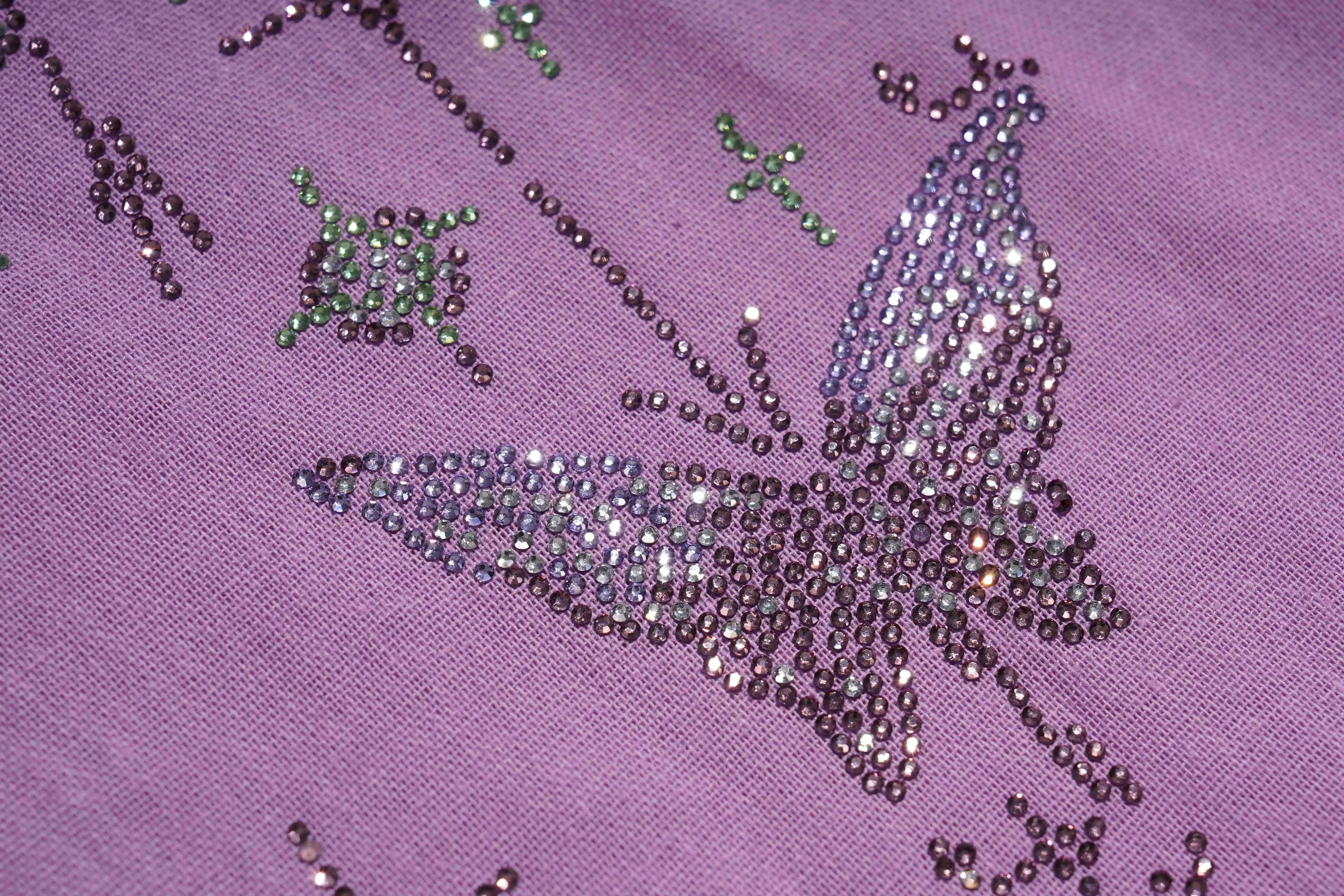 Close-up of a decorative butterfly design on purple fabric with rhinestones. TCH Purple Rhinestone Butterfly Set