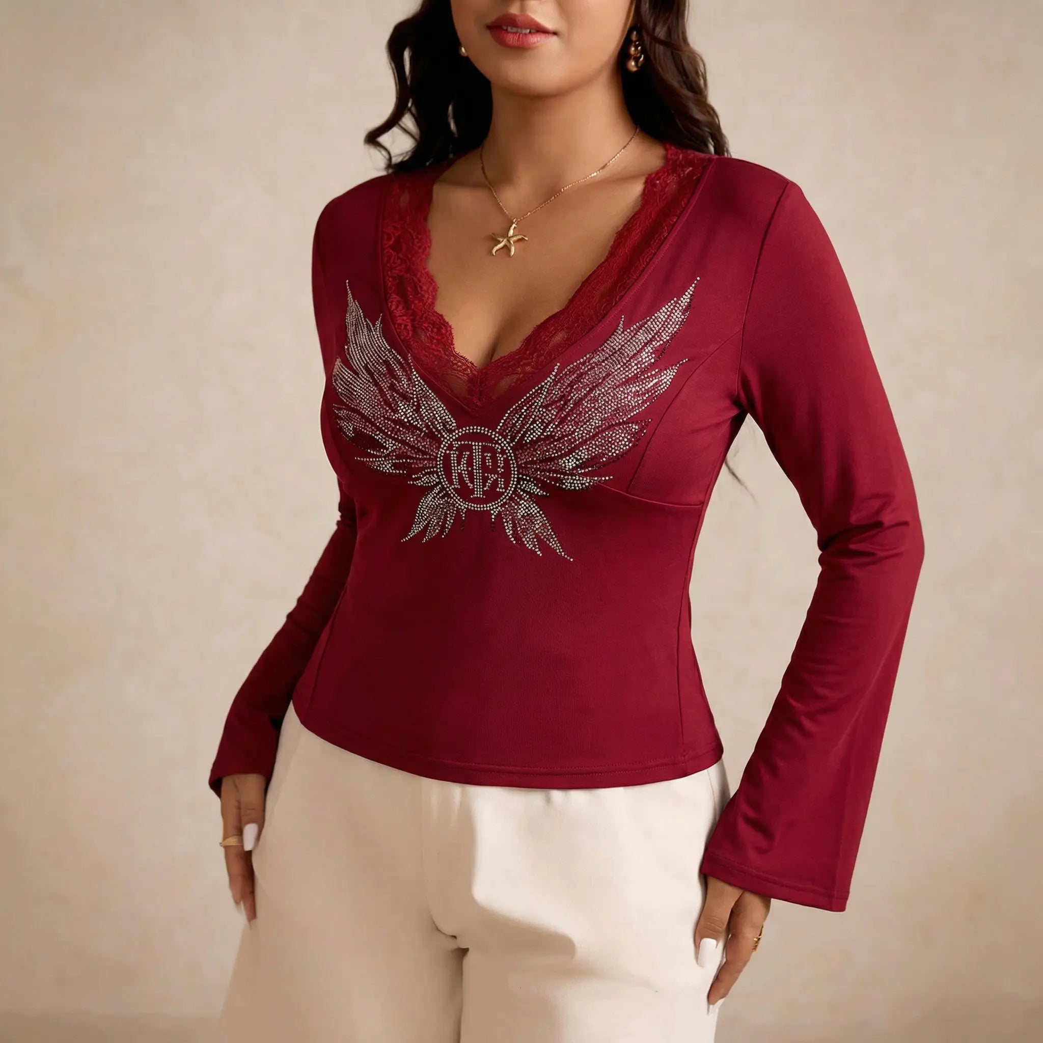 Red long-sleeve top with decorative wings and logo worn by a model on a beige background, TCH Red Lace Trim V-Neck Rhinestone Wing Long Sleeve Top
