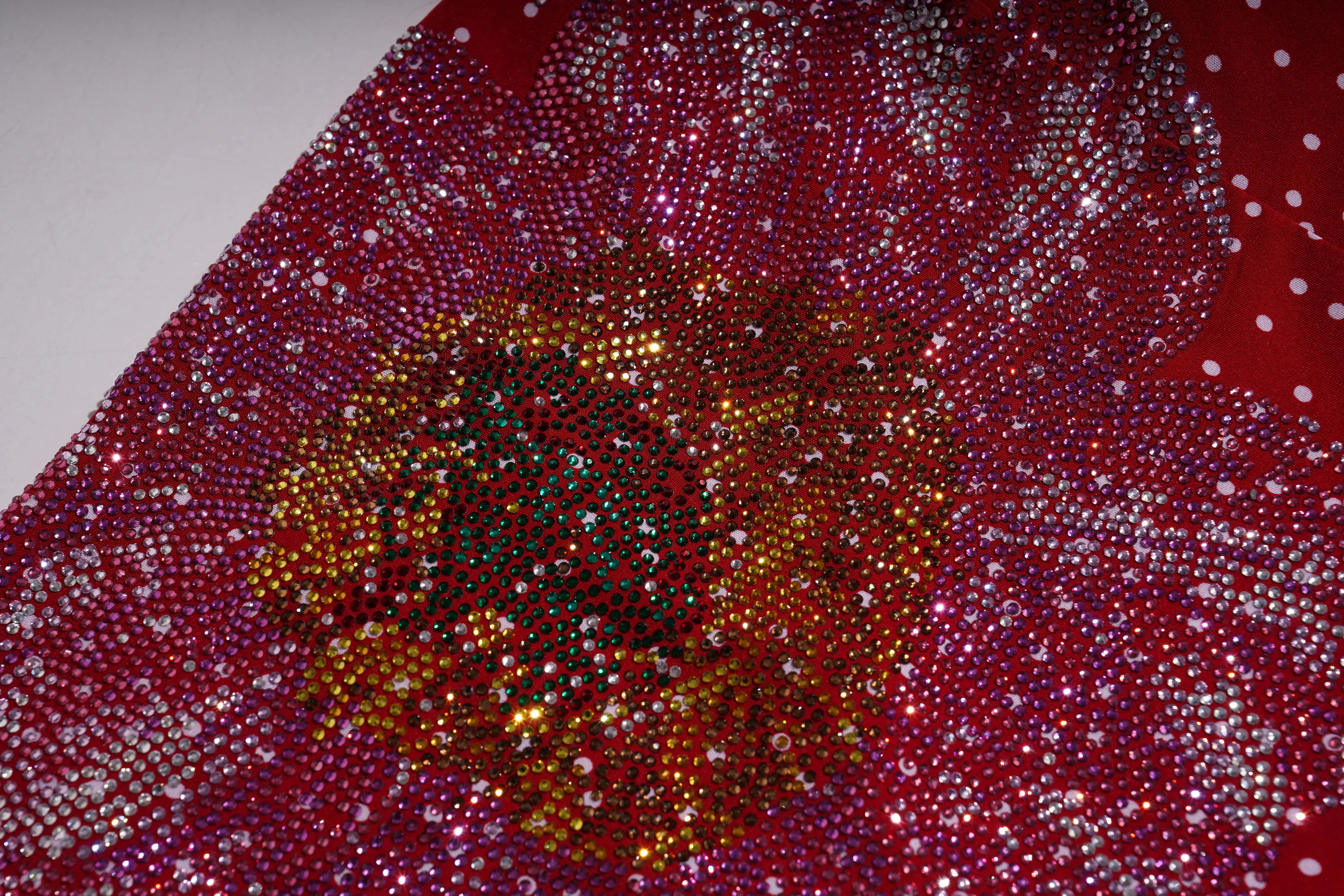 Close-up of a red fabric with a floral pattern made of small beads or stones. TCH Red Polka Dot Rhinestone Flower Dress