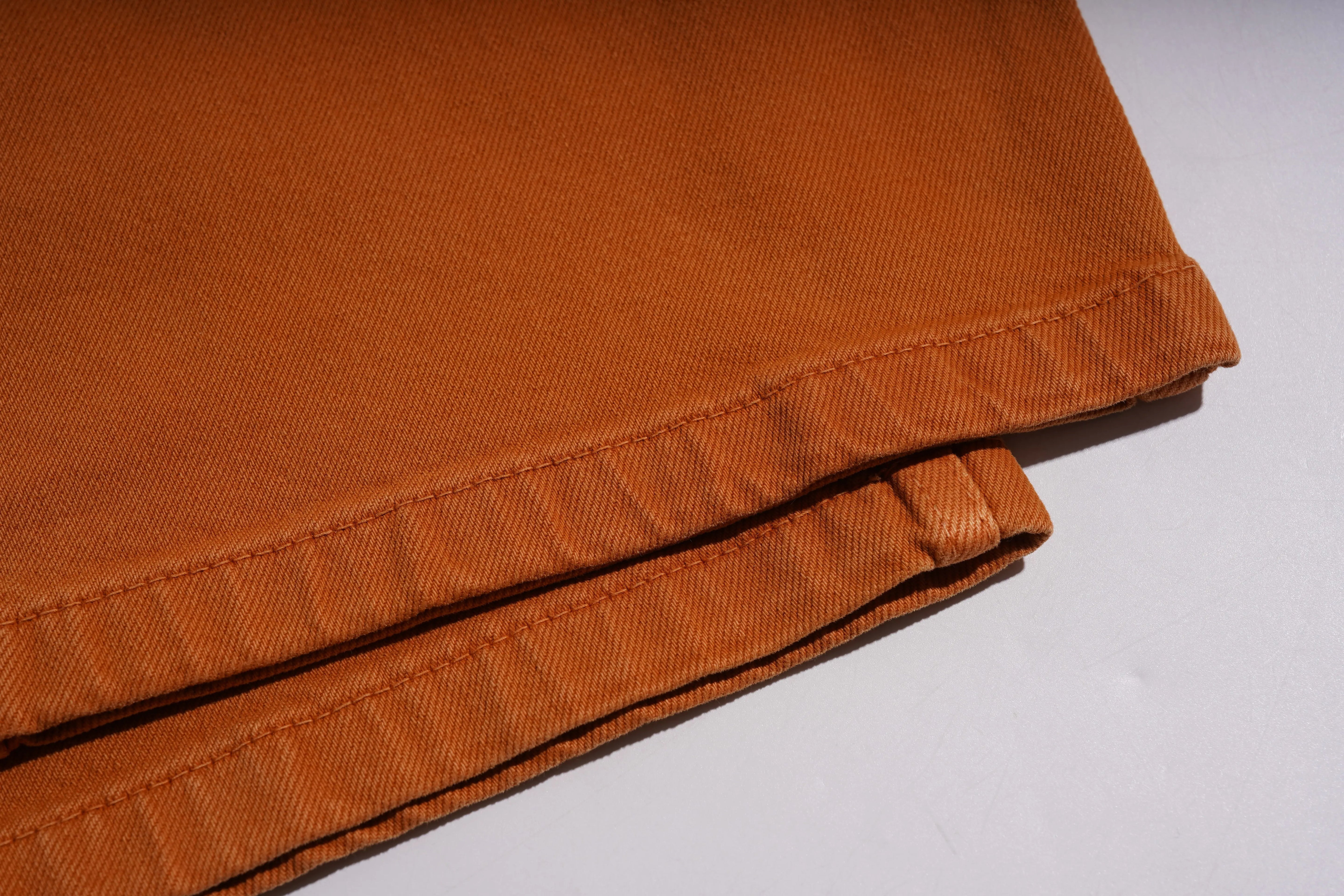 Close-up of a folded orange fabric on a white background, TCH Red Snowflake Rhinestone Brown Denim Jeans