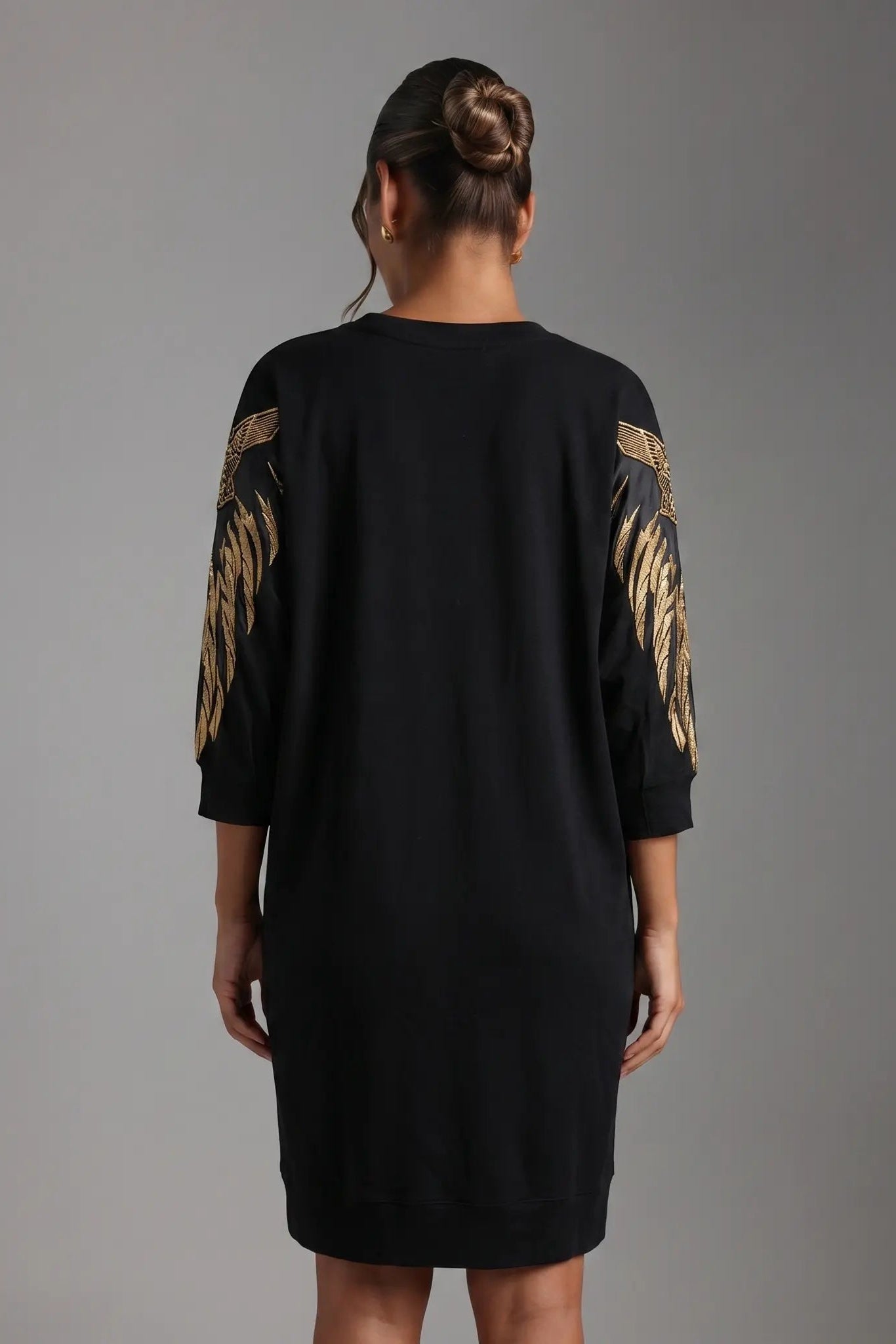 Person wearing a black dress with gold embroidery on sleeves against a gray background, TCH Rhinestone Angel Wing Black Dress