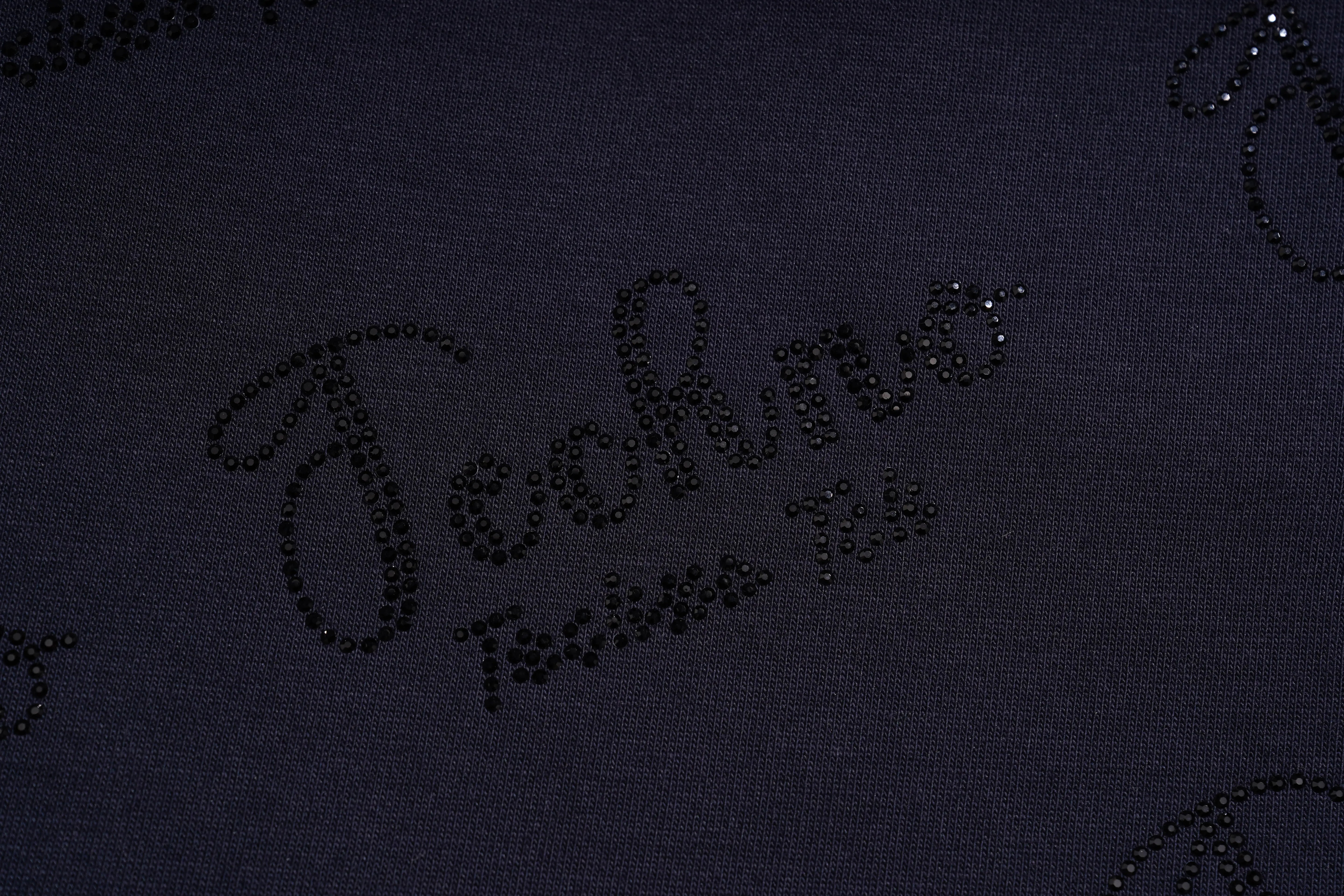 Close-up of a dark navy fabric with black rhinestone lettering that reads 'Fashion Town'. TCH Rhinestone Angel Wing Gradient Cargo Shorts