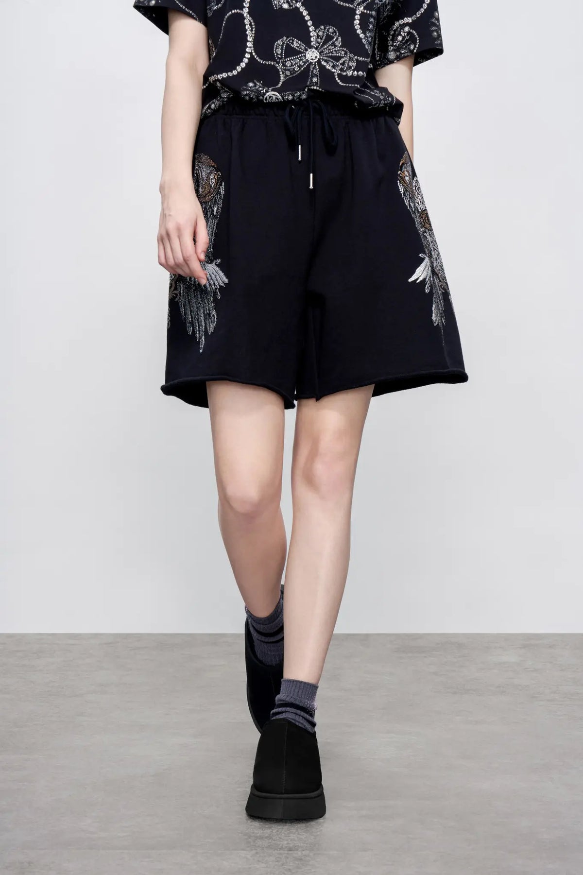 TCH Rhinestone Angel Wings Black Sweat Shorts TCH angel wings shorts Rhinestone black sweat shorts Black graphic shorts Angel wing sweat shorts Embellished black shorts Rhinestone streetwear shorts Y2K black shorts Relaxed fit sweat shorts Gothic graphic shorts Black casual drawstring shorts