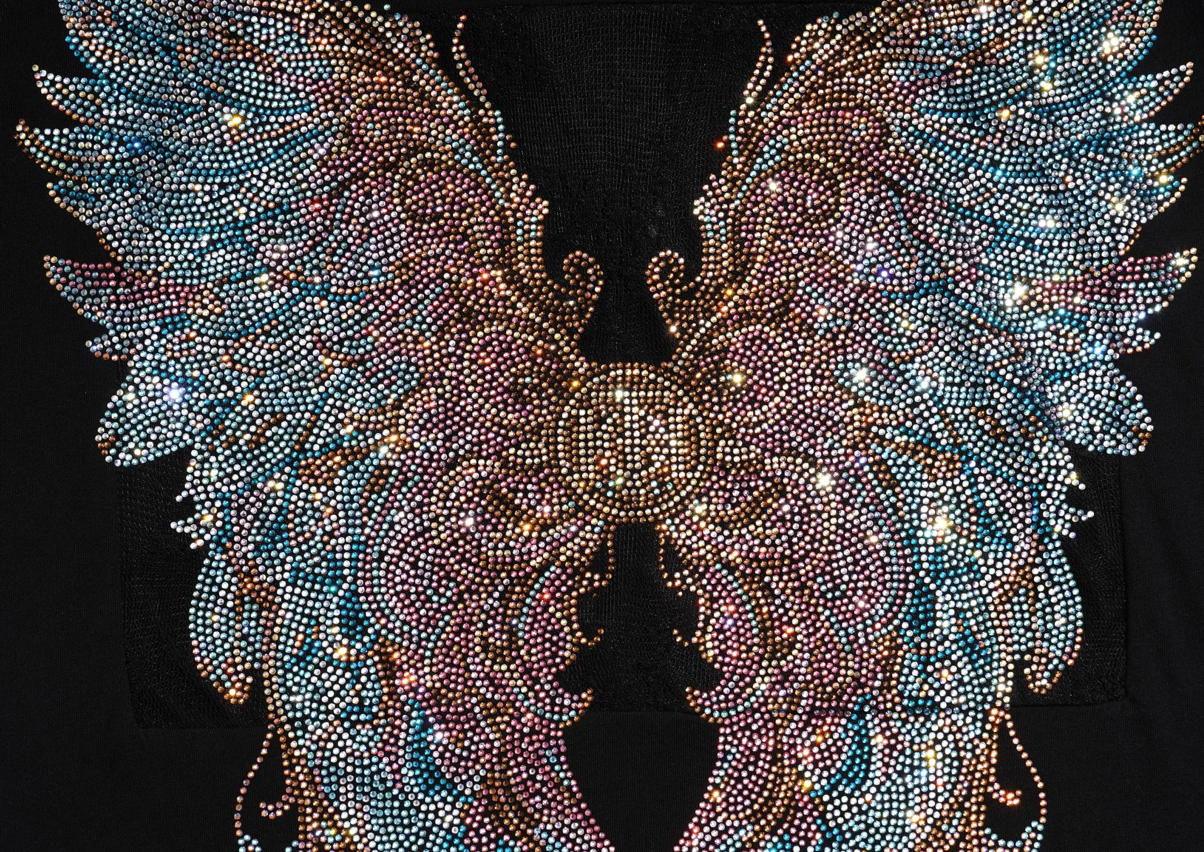 A pair of large, ornate angel wings covered in dense rhinestones and crystals, featuring a gradient of blue, pink, and gold tones against a solid black background. TCH Rhinestone Angel Wings Graphic T-Shirt