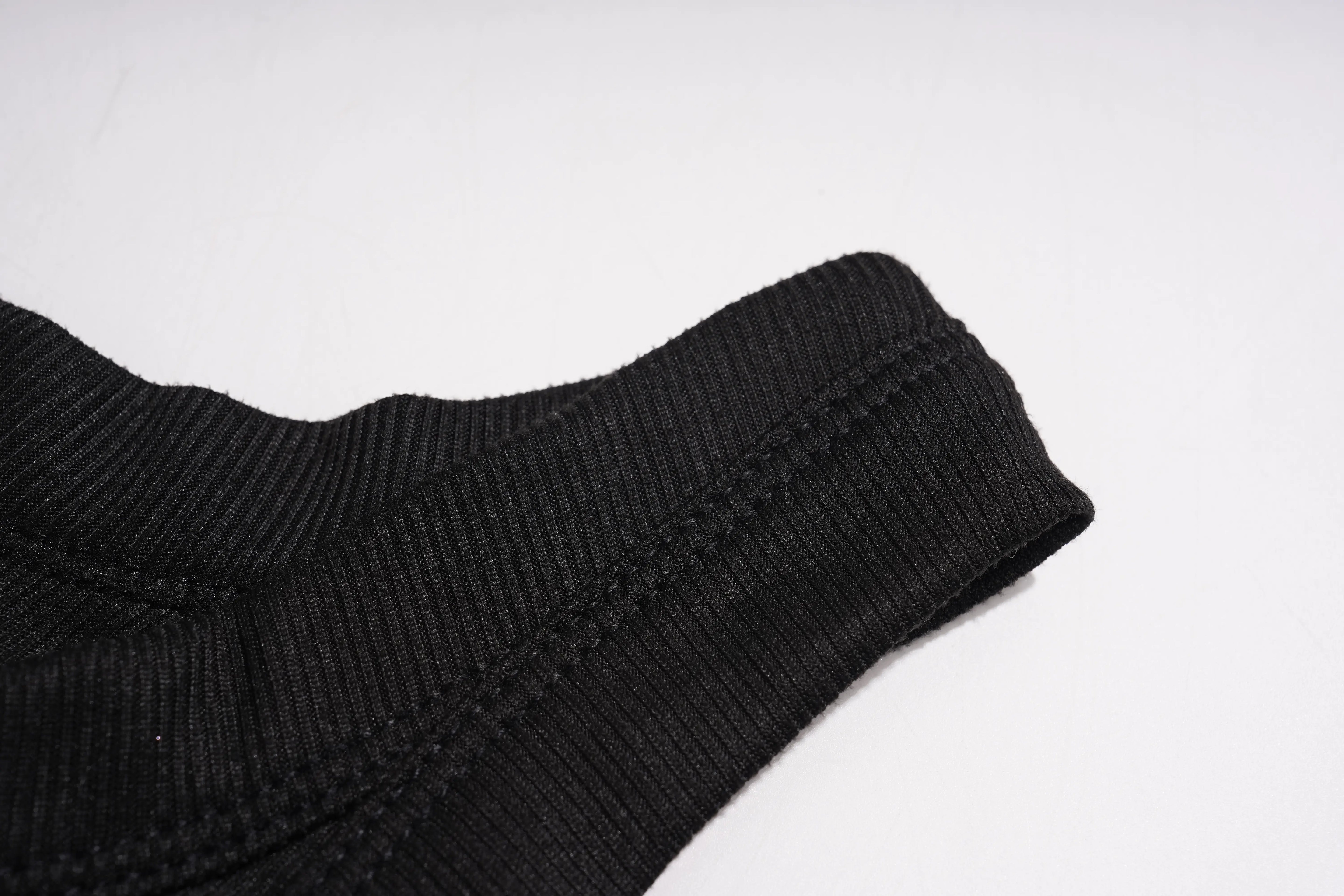 Close-up of a black ribbed knit garment, showing the texture and folded cuff on a plain white background. TCH Rhinestone Angel Wings Ribbed Tank Top