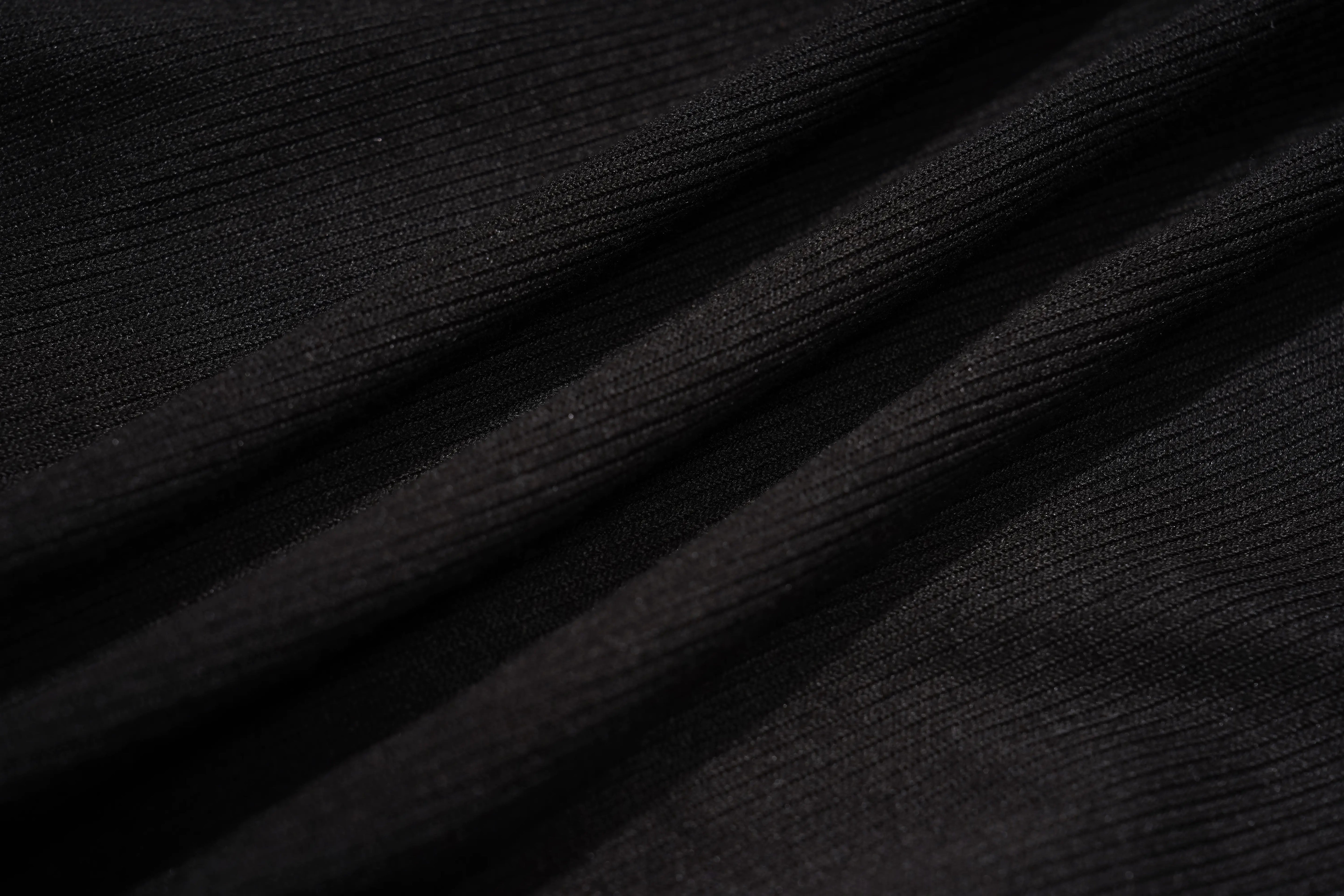 Close-up of a black ribbed fabric texture with soft diagonal folds and a fine knit pattern. TCH Rhinestone Angel Wings Ribbed Tank Top