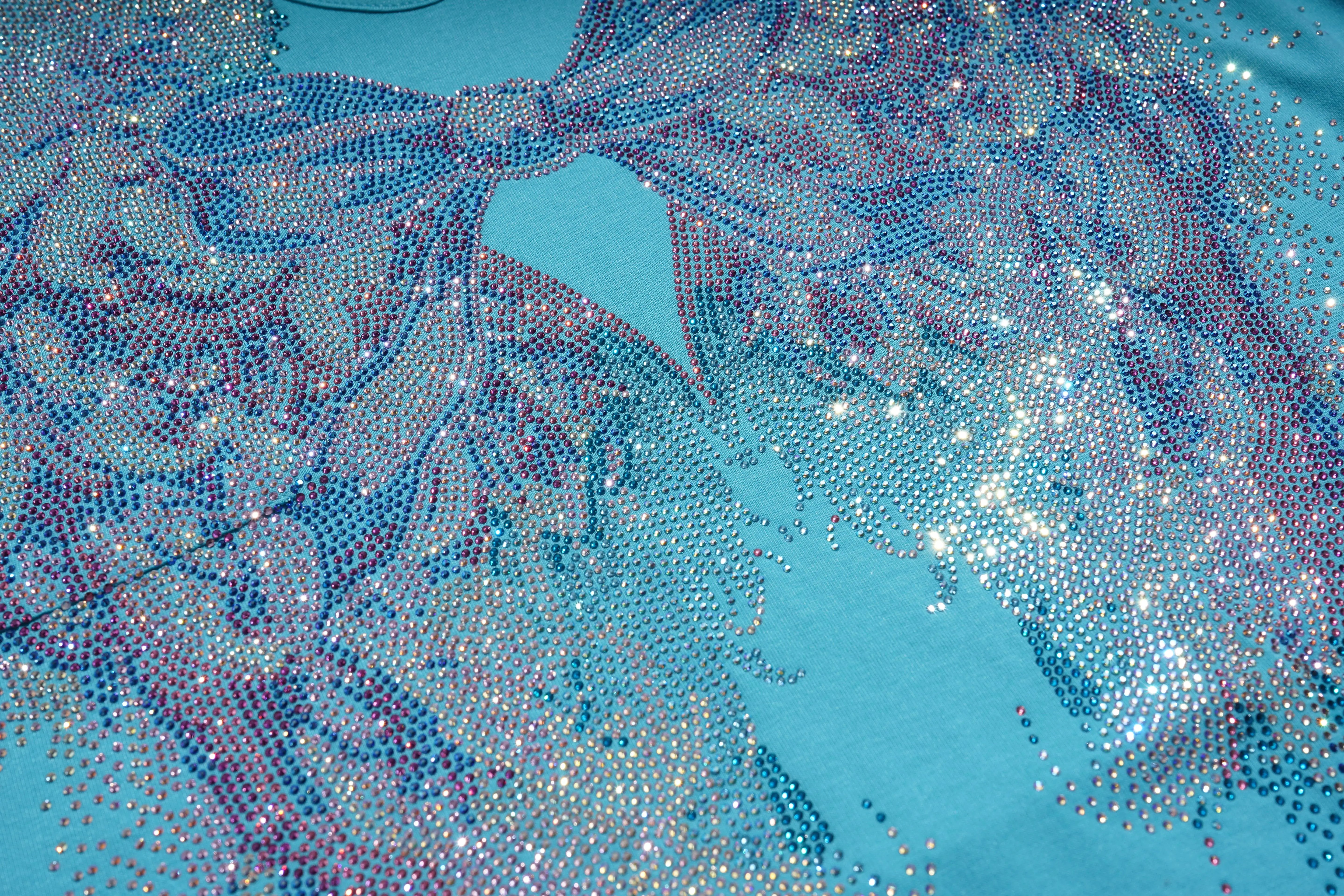 Close-up of a decorative fabric with intricate patterns and embellishments on a blue background, TCH Rhinestone Angel Wings V-Neck T-Shirt