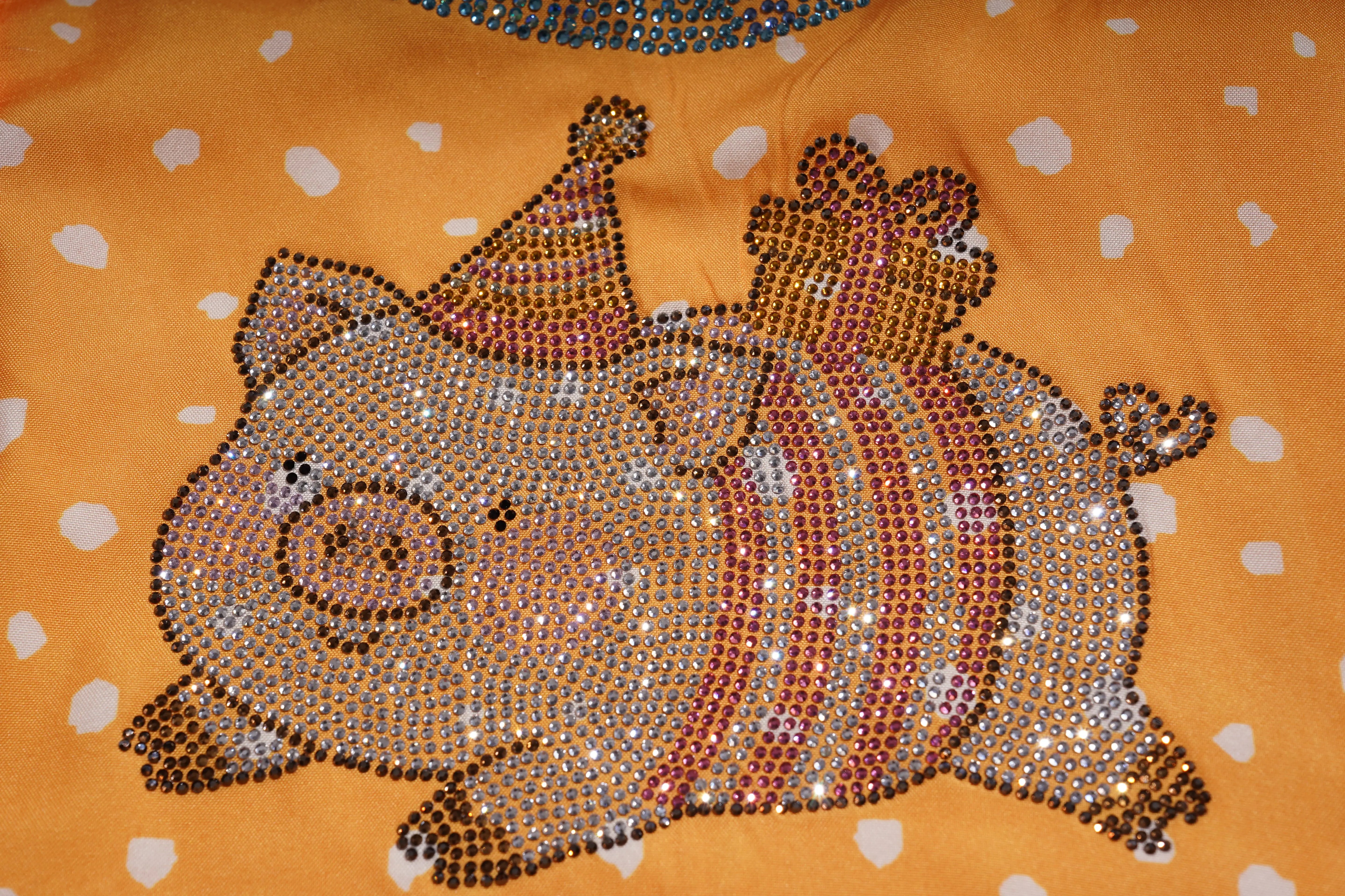 Decorative pillow with a pig design made of rhinestones on an orange background with white polka dots. TCH Rhinestone Animal Polka Dot Shirt