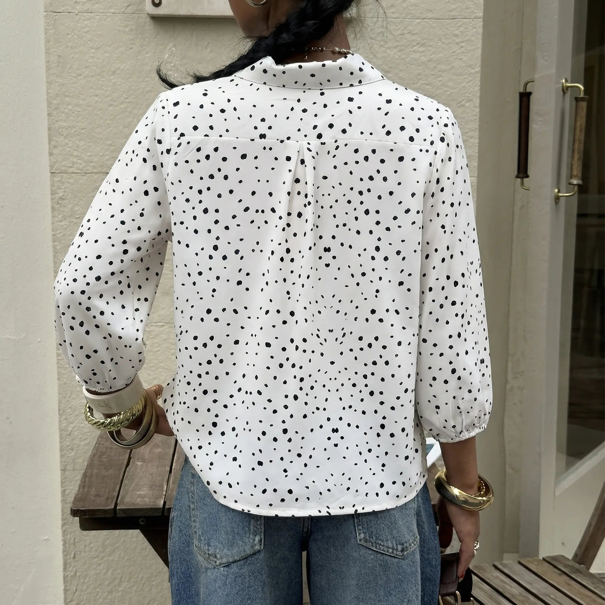 Person wearing a white shirt with black polka dots and blue jeans, standing outdoors. TCH Rhinestone Animal Polka Dot Shirt
