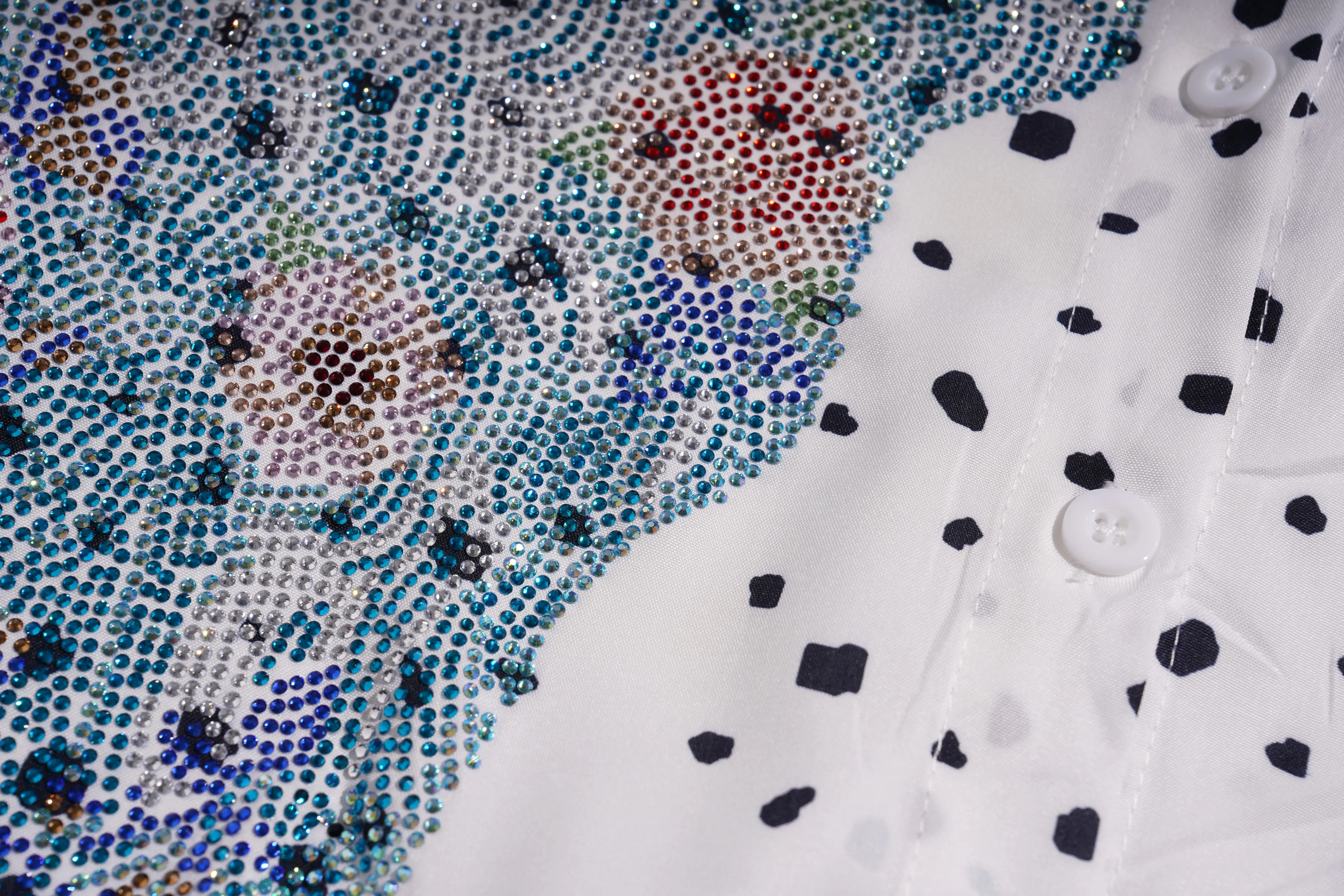 Close-up of a fabric with colorful beadwork and a white shirt with black polka dots. TCH Rhinestone Animal Polka Dot Shirt