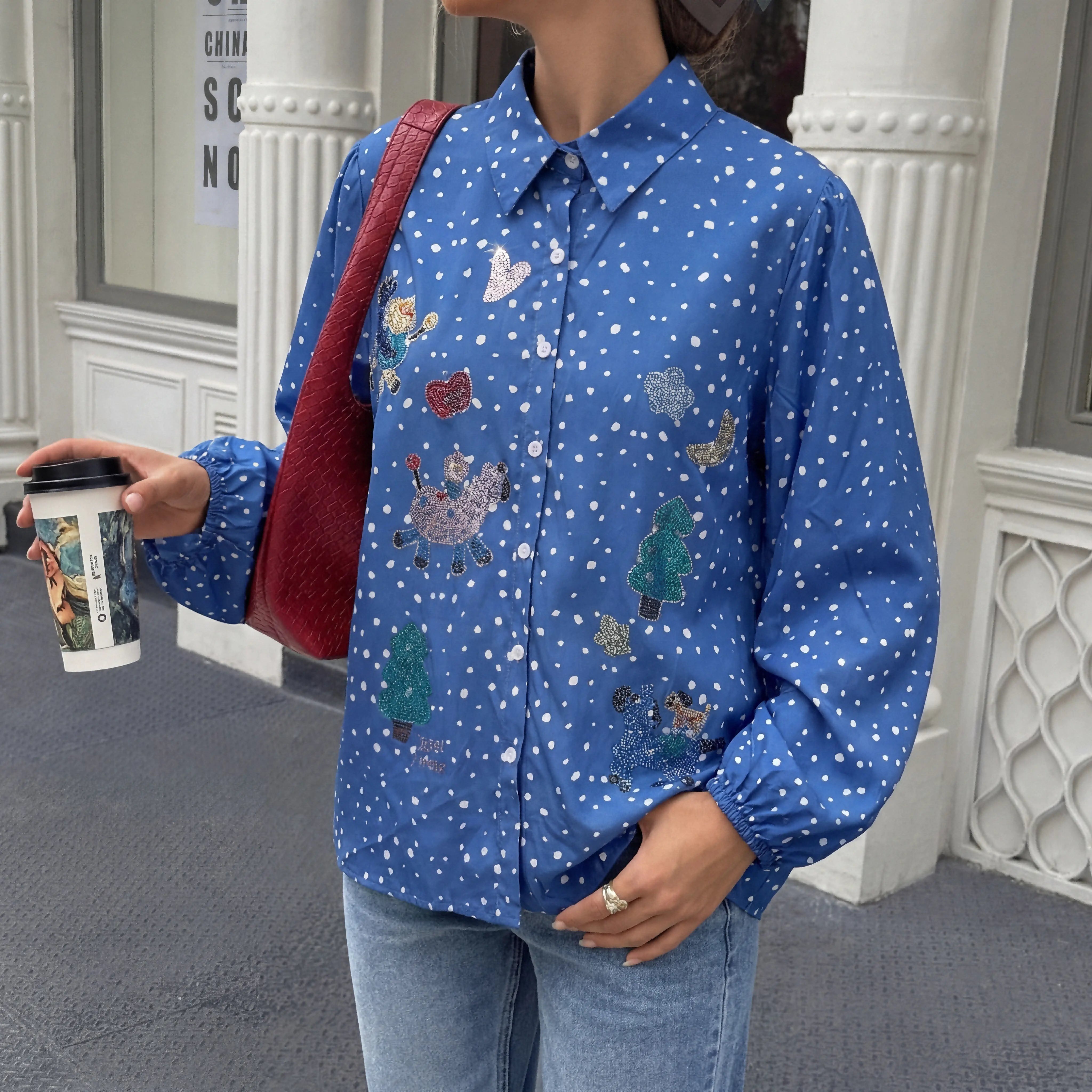Person wearing a blue patterned shirt holding a coffee cup and a red bag. TCH Rhinestone Animal Polka Dot Shirt