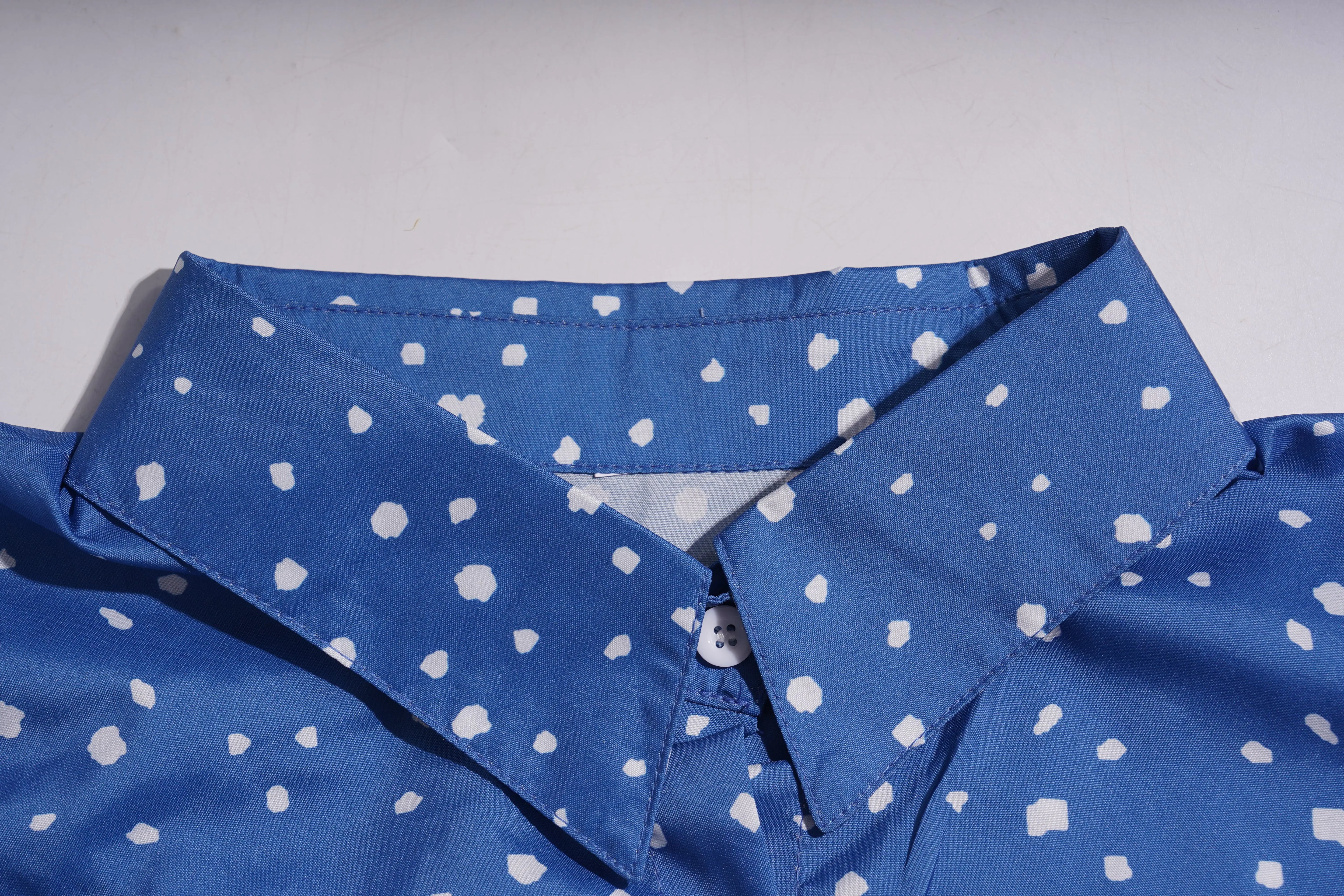 Close-up of a blue shirt with white polka dot pattern on a light gray background, TCH Rhinestone Animal Polka Dot Shirt