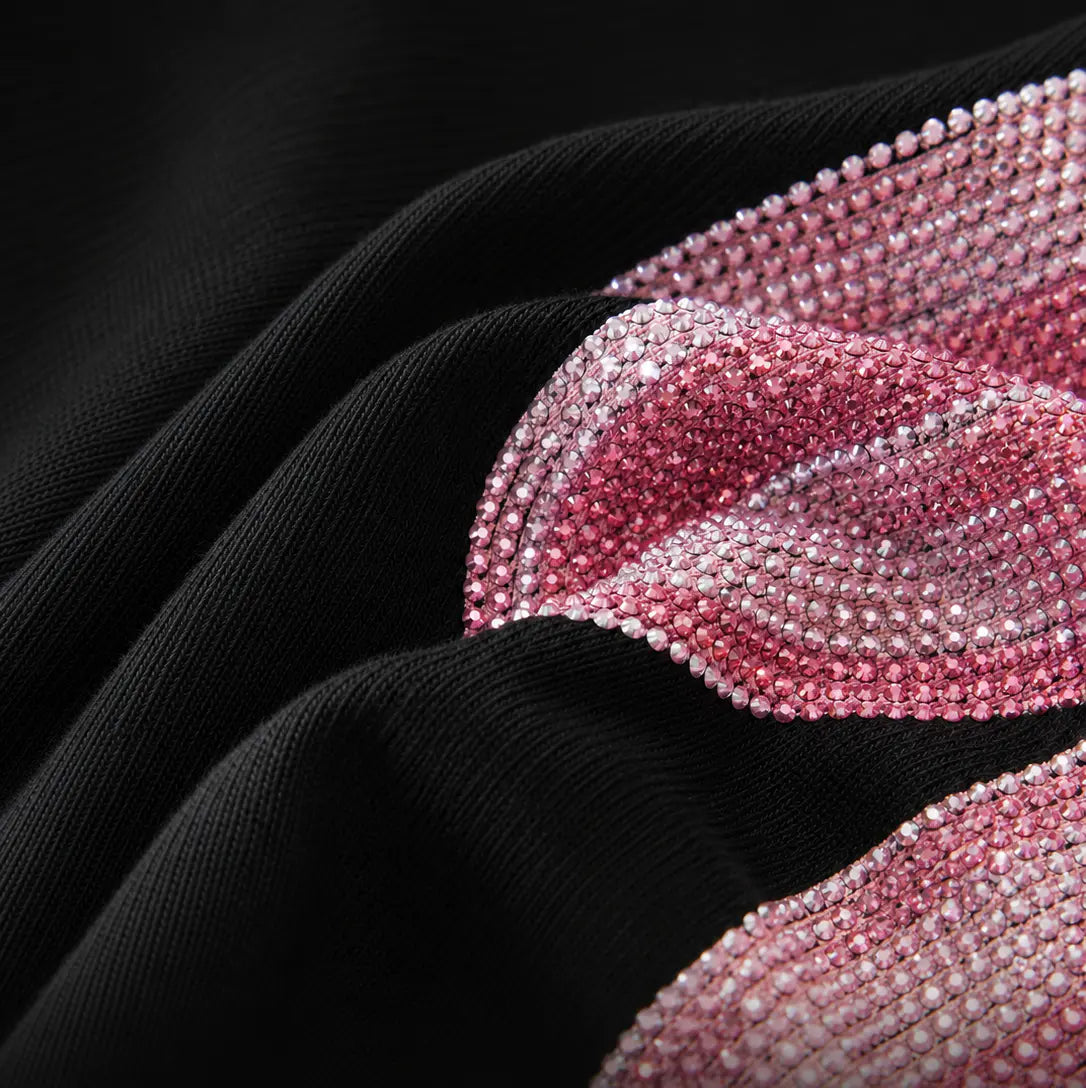 Close-up of a black textured fabric garment with a wavy band of pink rhinestone embellishment. TCH Rhinestone Bow Collar Black Mini Dress