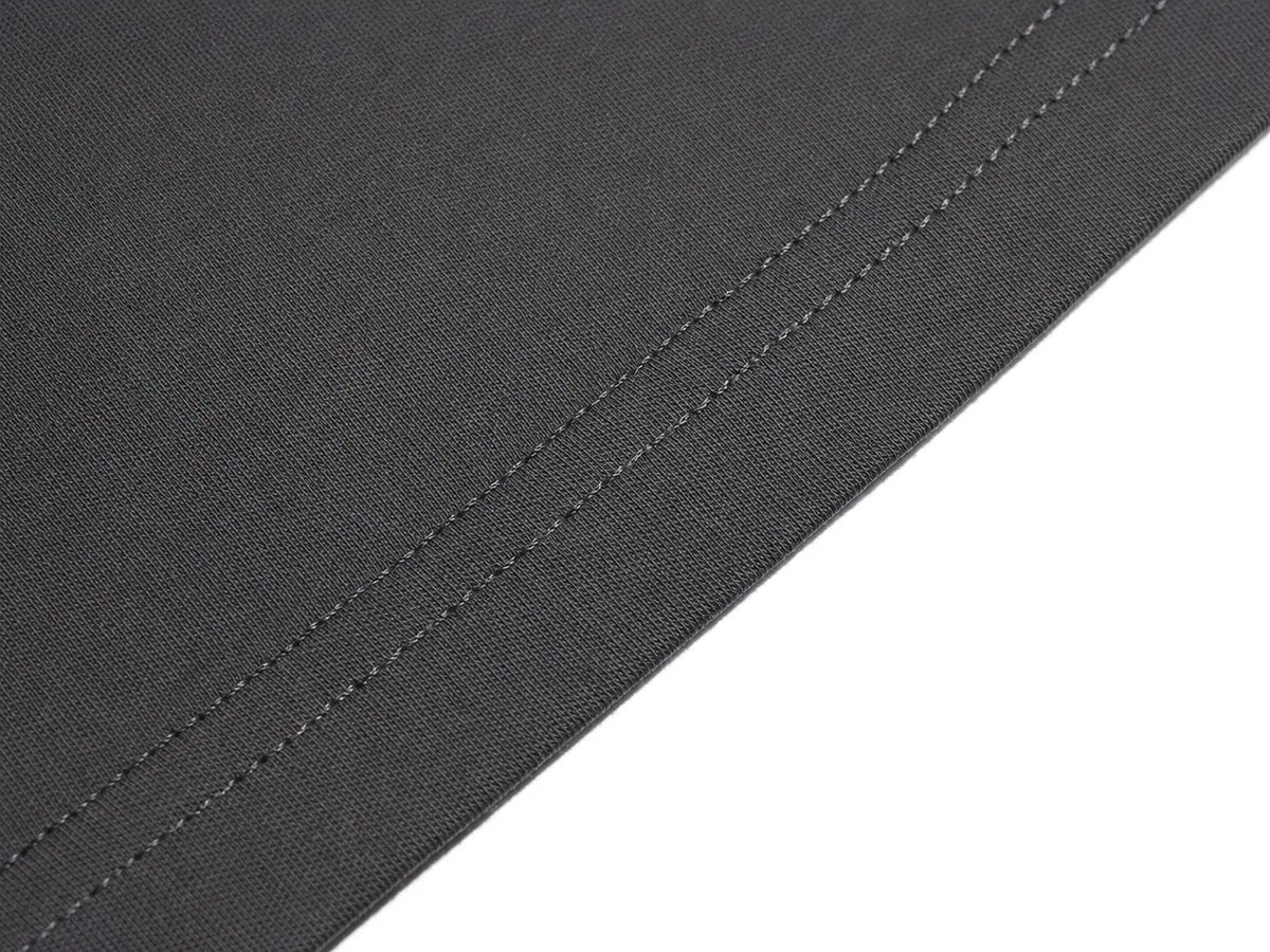 Close-up of a dark charcoal gray woven fabric with a double stitched edge, shown against a plain white background. TCH Rhinestone Bow Graphic Fitted Long Sleeve Top