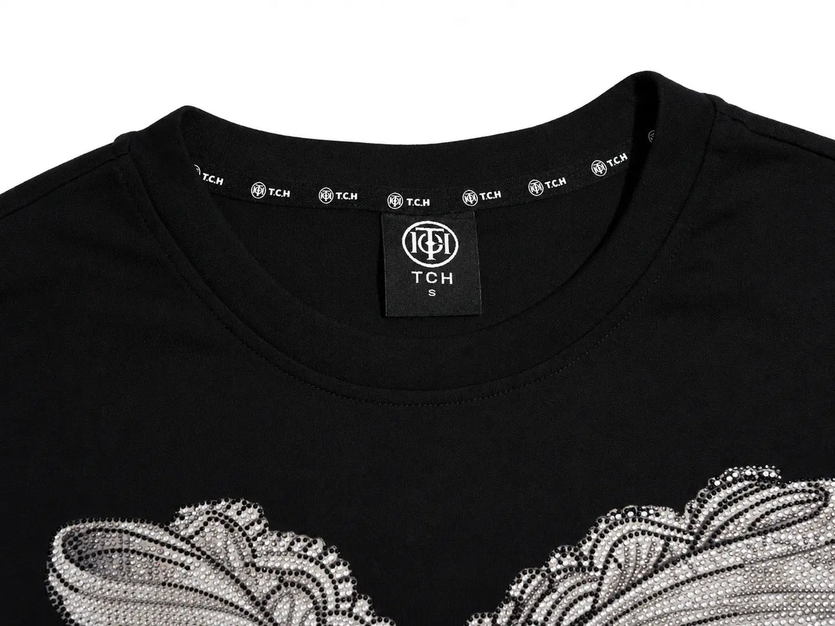 Close-up of a black crewneck T-shirt with a silver and white textured graphic across the chest and a visible TCH neck label. TCH Rhinestone Bow Graphic Fitted Long Sleeve Top