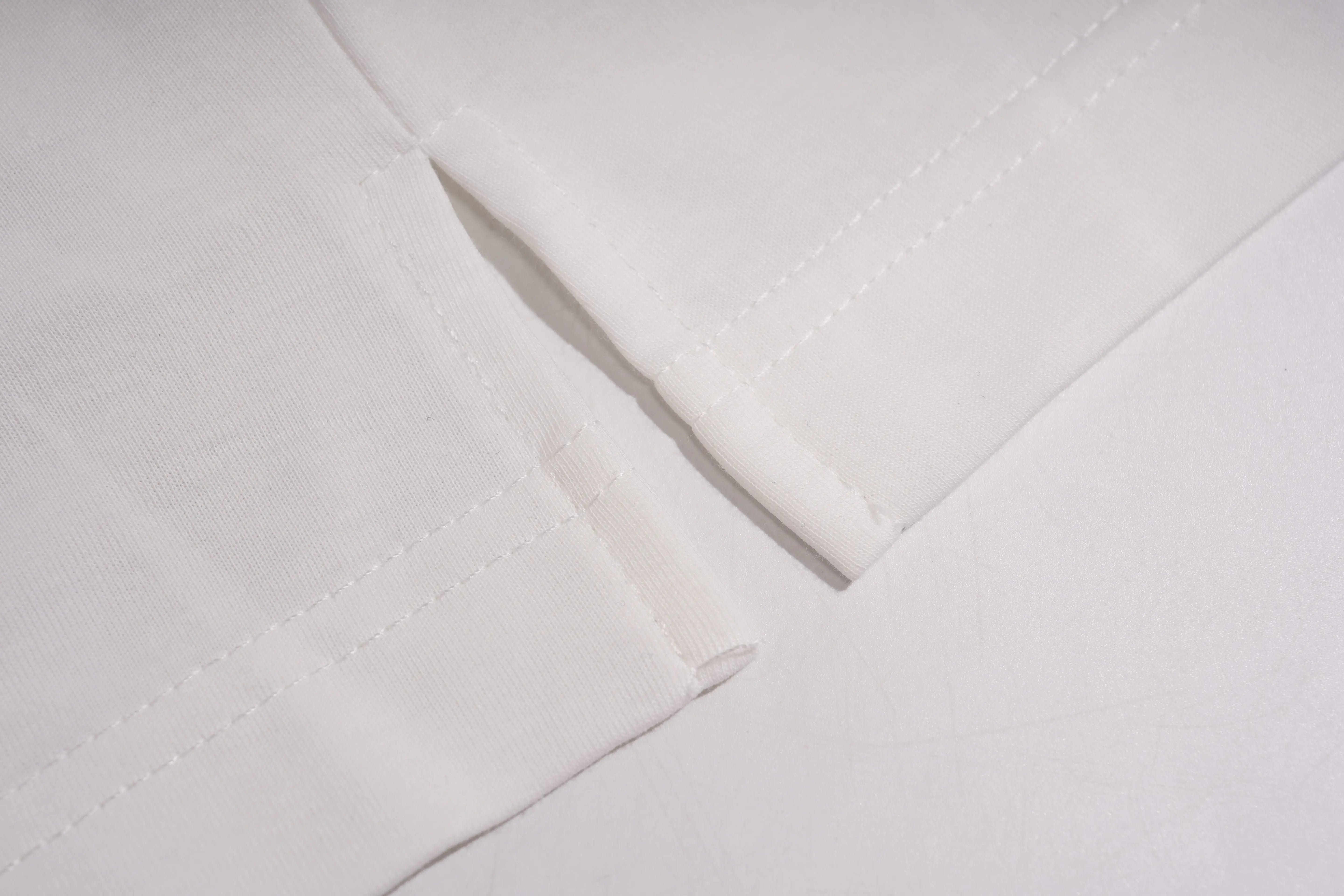 Close-up of a white fabric item showing folded edges and fine stitching on a white background. TCH Rhinestone Bow Graphic Oversized T-Shirt Dress