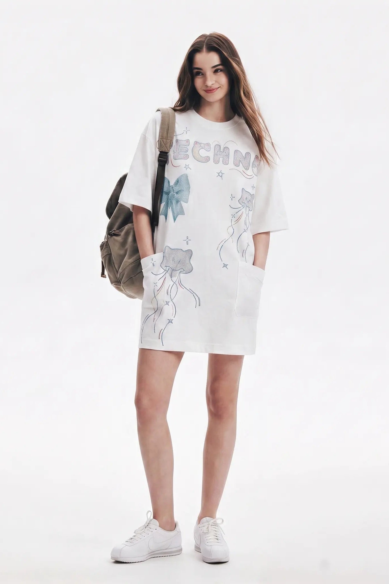 A woman modeling an oversized white graphic T-shirt dress with jellyfish illustrations and the word 'ECHO' printed across the chest, styled with a brown backpack and white sneakers against a plain white studio background. TCH Rhinestone Bow Graphic Oversized T-Shirt Dress