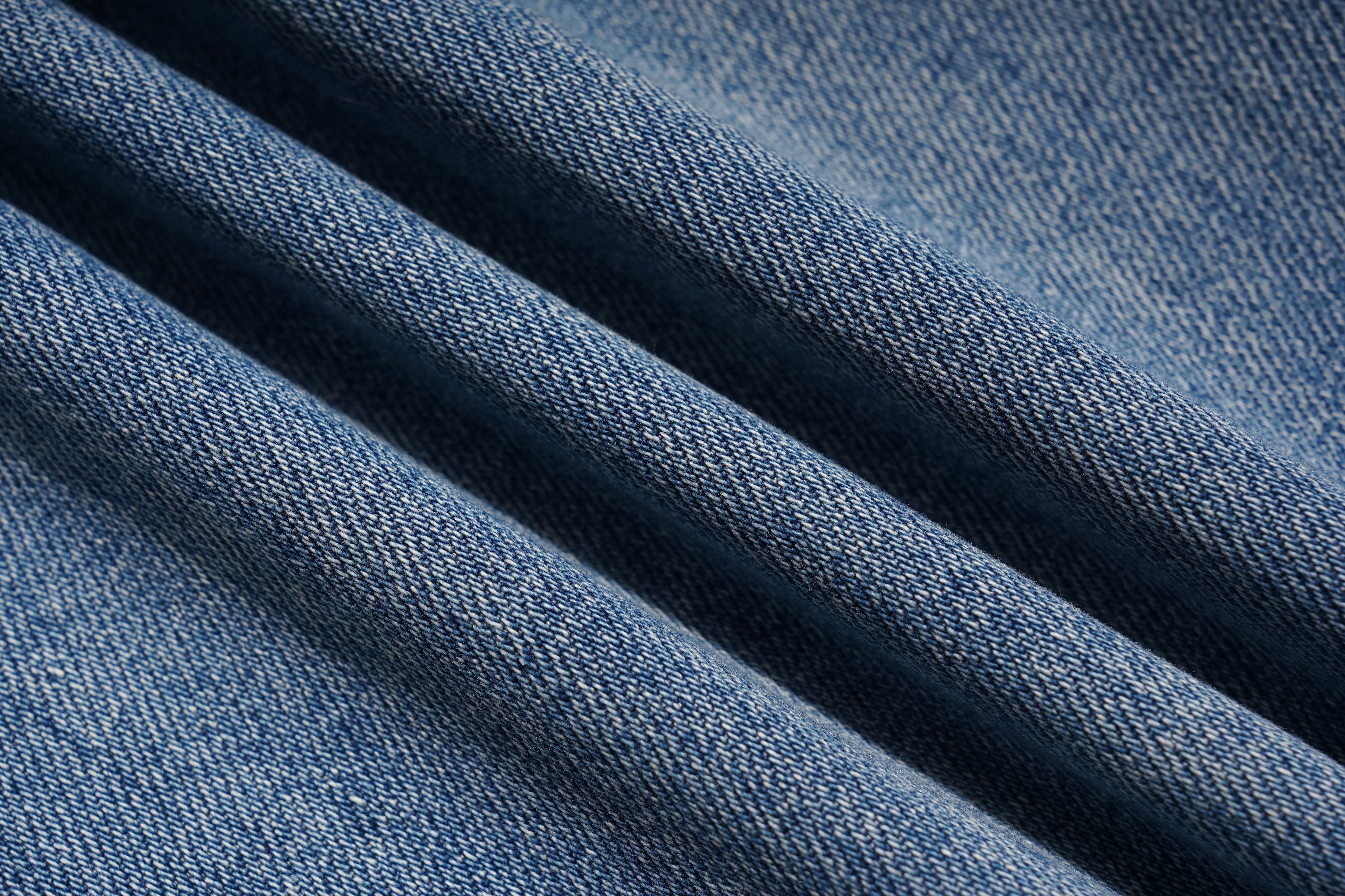 A close-up of blue denim fabric with diagonal folds showing the woven texture. TCH Rhinestone Bow Lace Side Panel Wide Leg Jeans