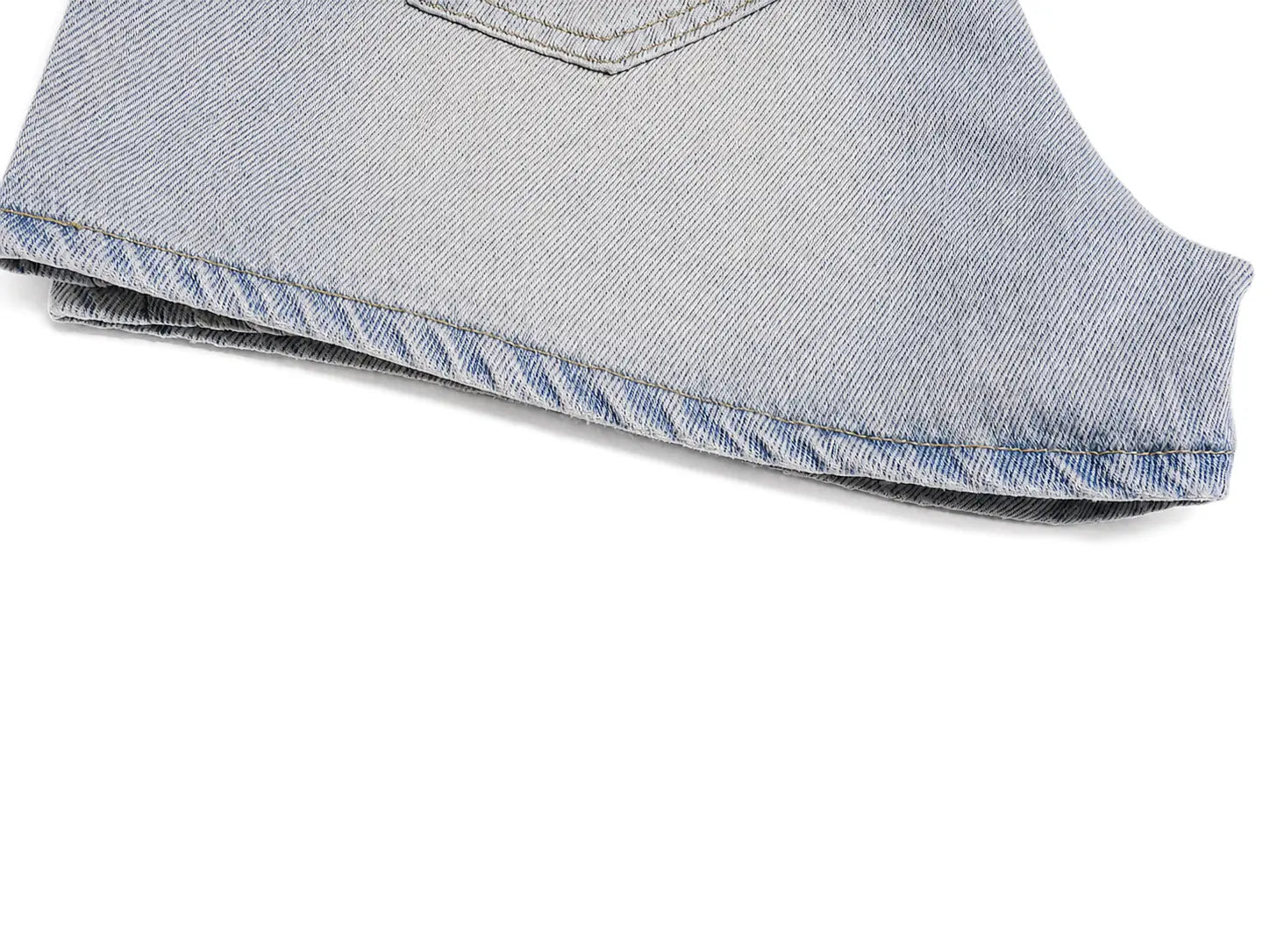 A close-up detail shot of a folded pair of light-wash blue denim jeans on a solid white background, showing the texture of the denim fabric and the hem stitching. TCH Rhinestone Bow Light Wash Denim Shorts