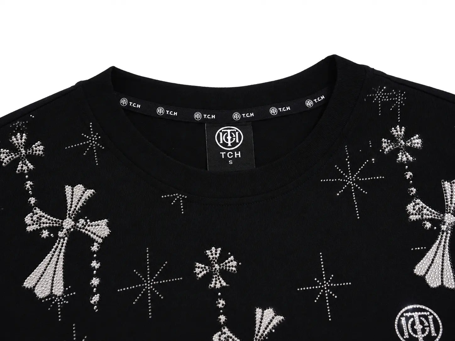 Close-up of a black crewneck sweatshirt featuring rhinestone-embellished crosses and starburst patterns, with a visible TCH neck label. TCH Rhinestone Bow Star Pattern Black T-Shirt