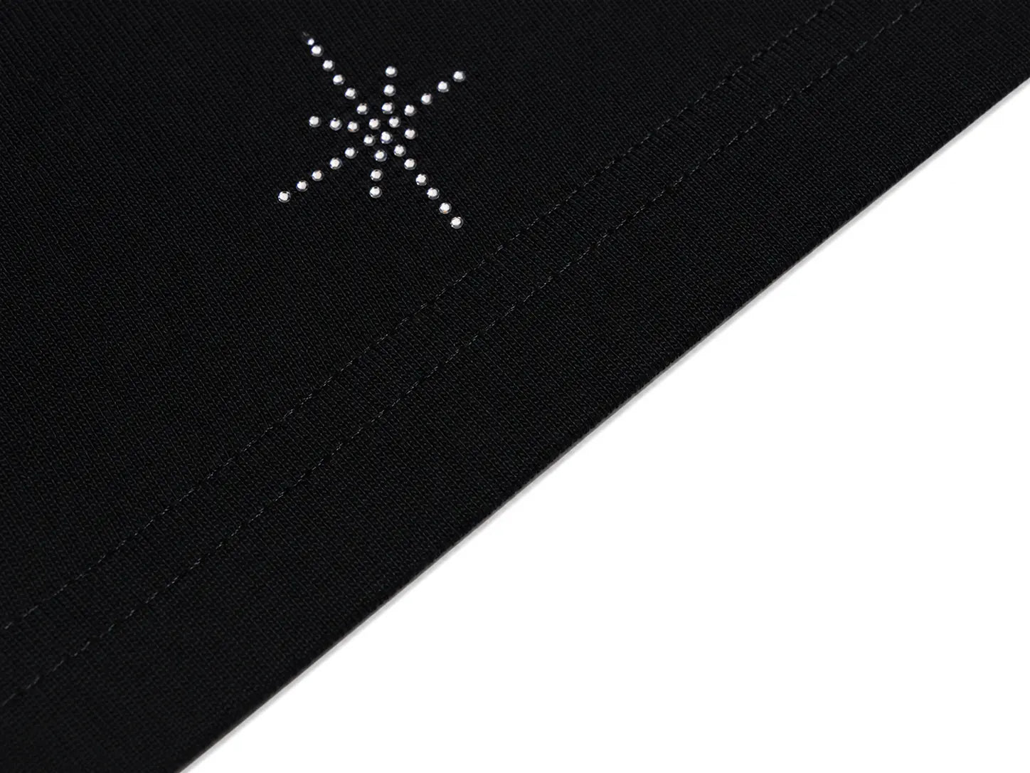 Close-up of a black fabric surface with a small white dotted starburst emblem near the upper left area, shown against a white background. TCH Rhinestone Bow Star Pattern Black T-Shirt