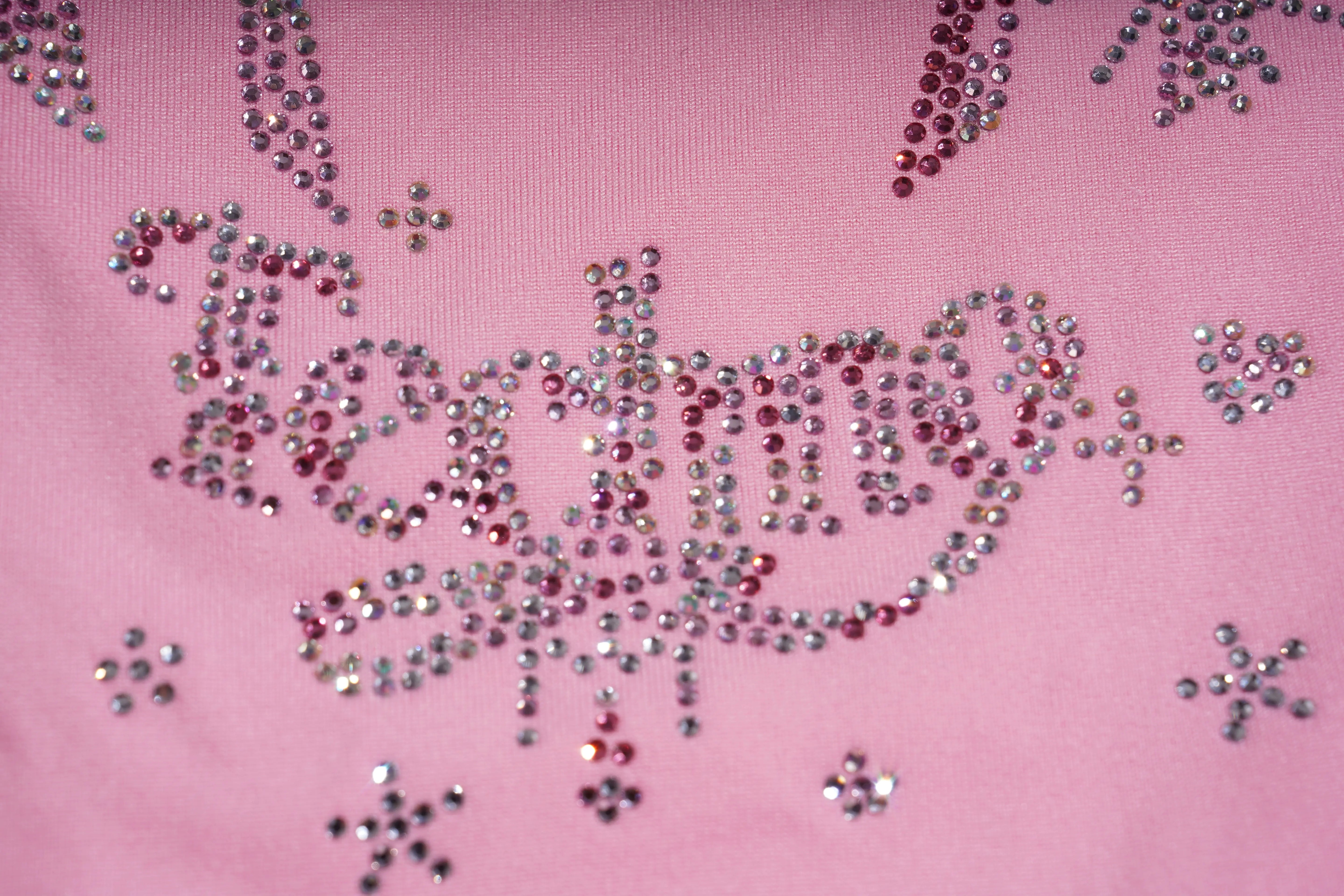 Pink fabric with decorative text and embellishments on a pink background, TCH Rhinestone Bow & Wing Set