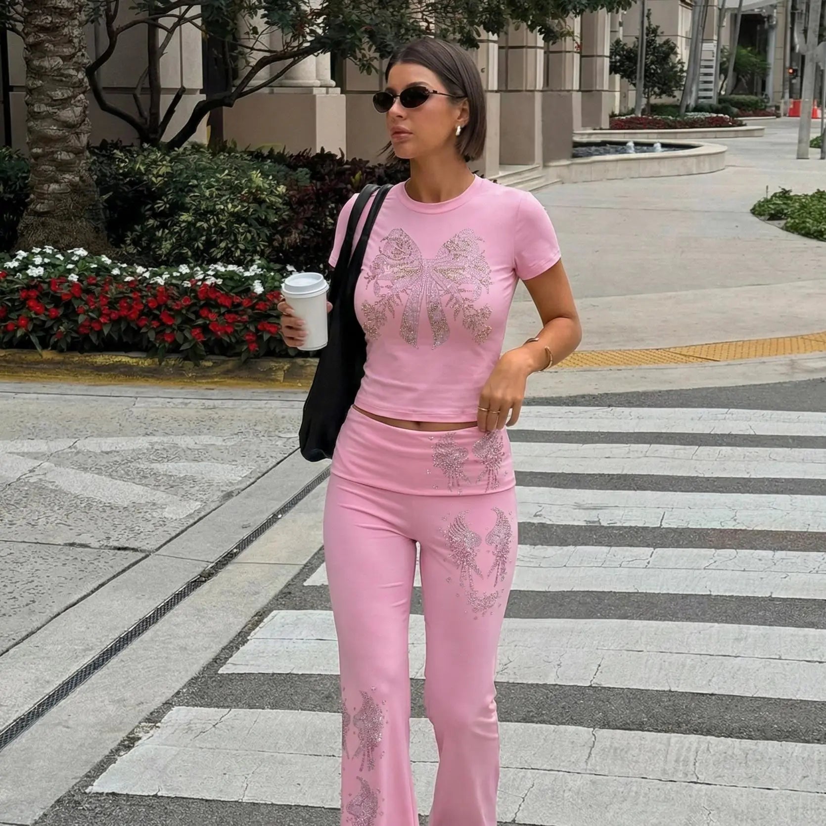 Woman in pink outfit walking on a sidewalk holding a coffee cup. TCH Rhinestone Bow & Wing Set