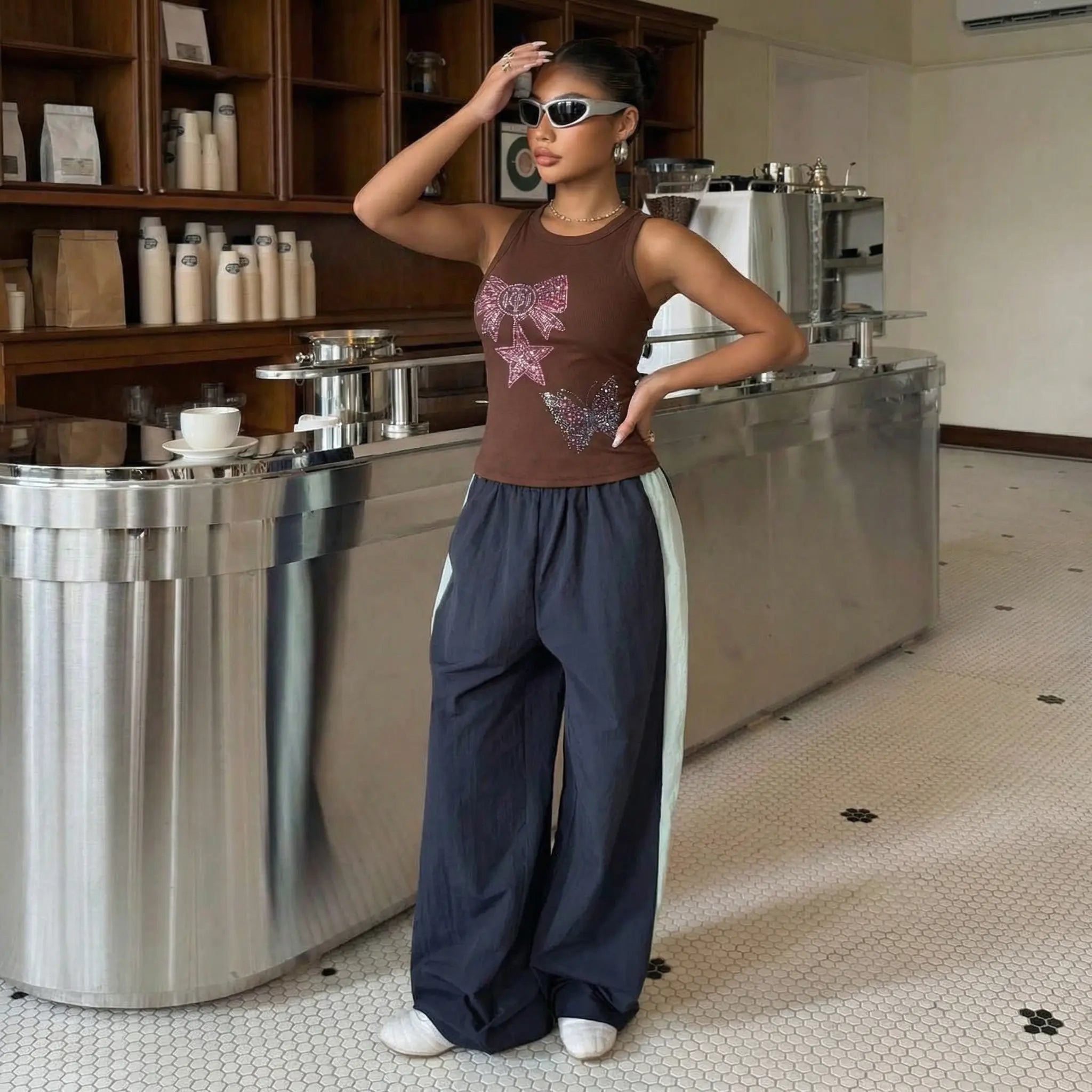 Woman posing in a modern kitchen with stainless steel appliances, TCH Rhinestone Butterfly Bow Tank Top