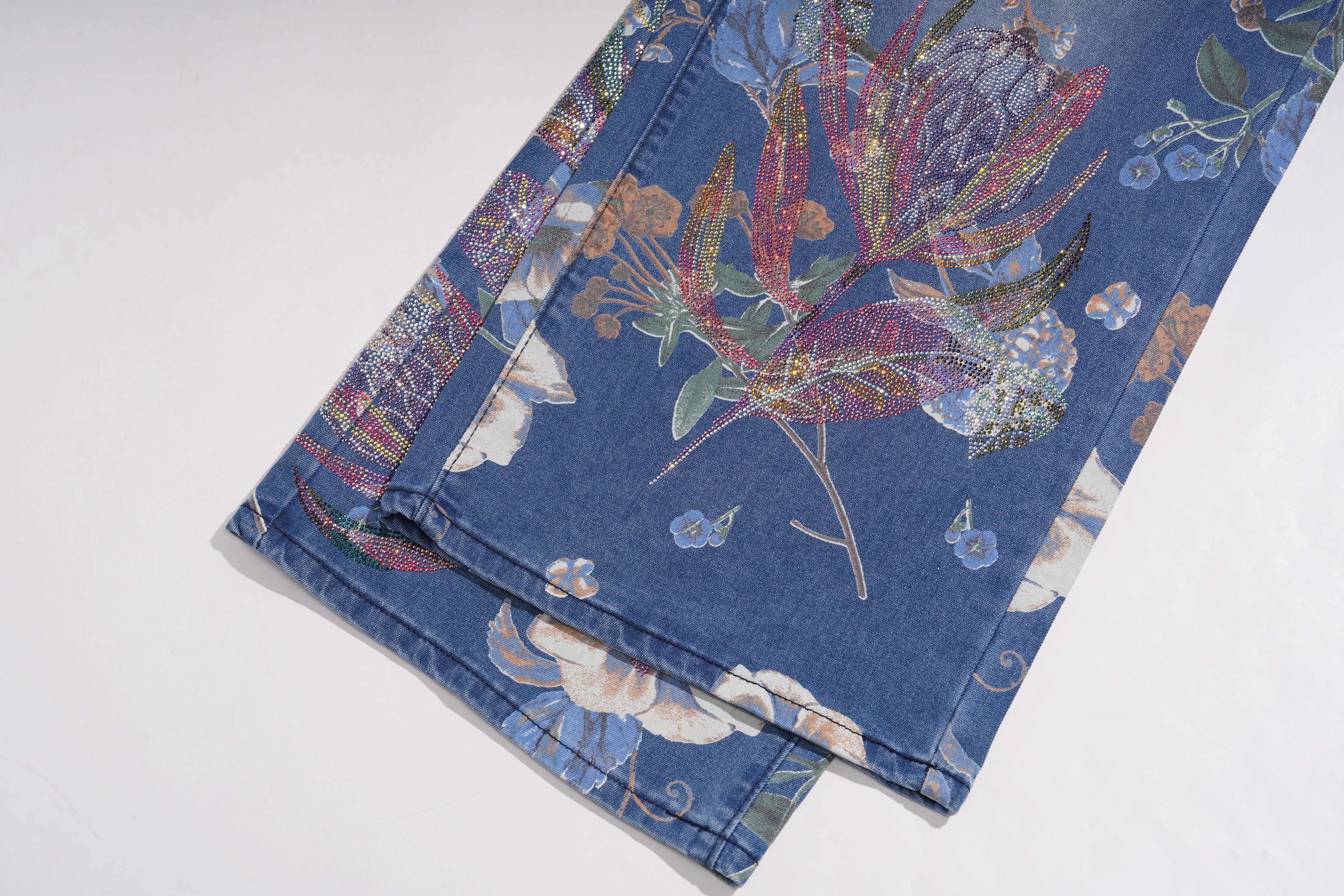 Folded denim fabric with floral embroidery on a white background, TCH Rhinestone Butterfly Floral Print Denim Jeans