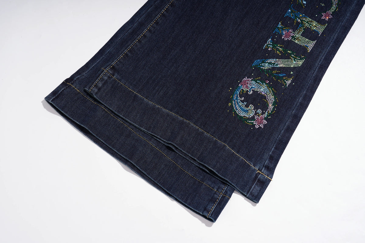 Close-up of a dark blue denim garment, likely a skirt or folded pants leg, featuring a colorful rhinestone-embellished graphic on the side. TCH Rhinestone Butterfly Graphic Wide-Leg Jeans