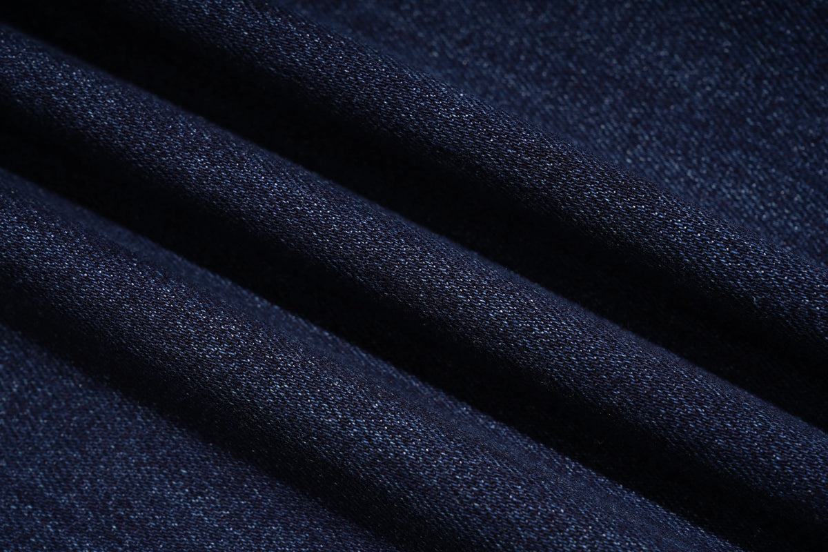 A close-up of dark navy blue fabric with soft diagonal folds showing a fine woven texture. TCH Rhinestone Butterfly Graphic Wide-Leg Jeans