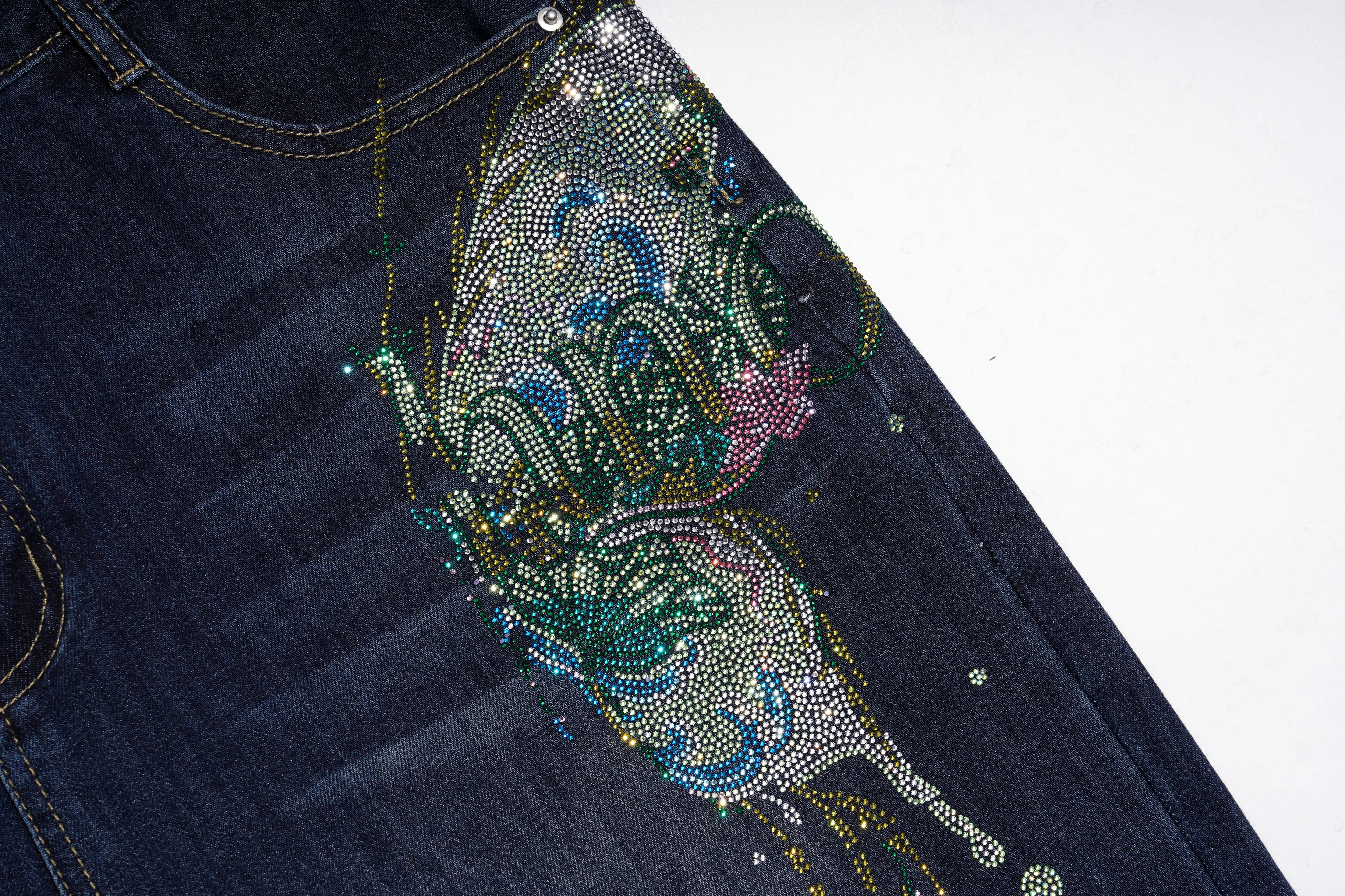 Close-up of dark blue denim jeans with a large, colorful rhinestone butterfly embellishment on the pocket area, set against a plain white background. TCH Rhinestone Butterfly Graphic Wide-Leg Jeans