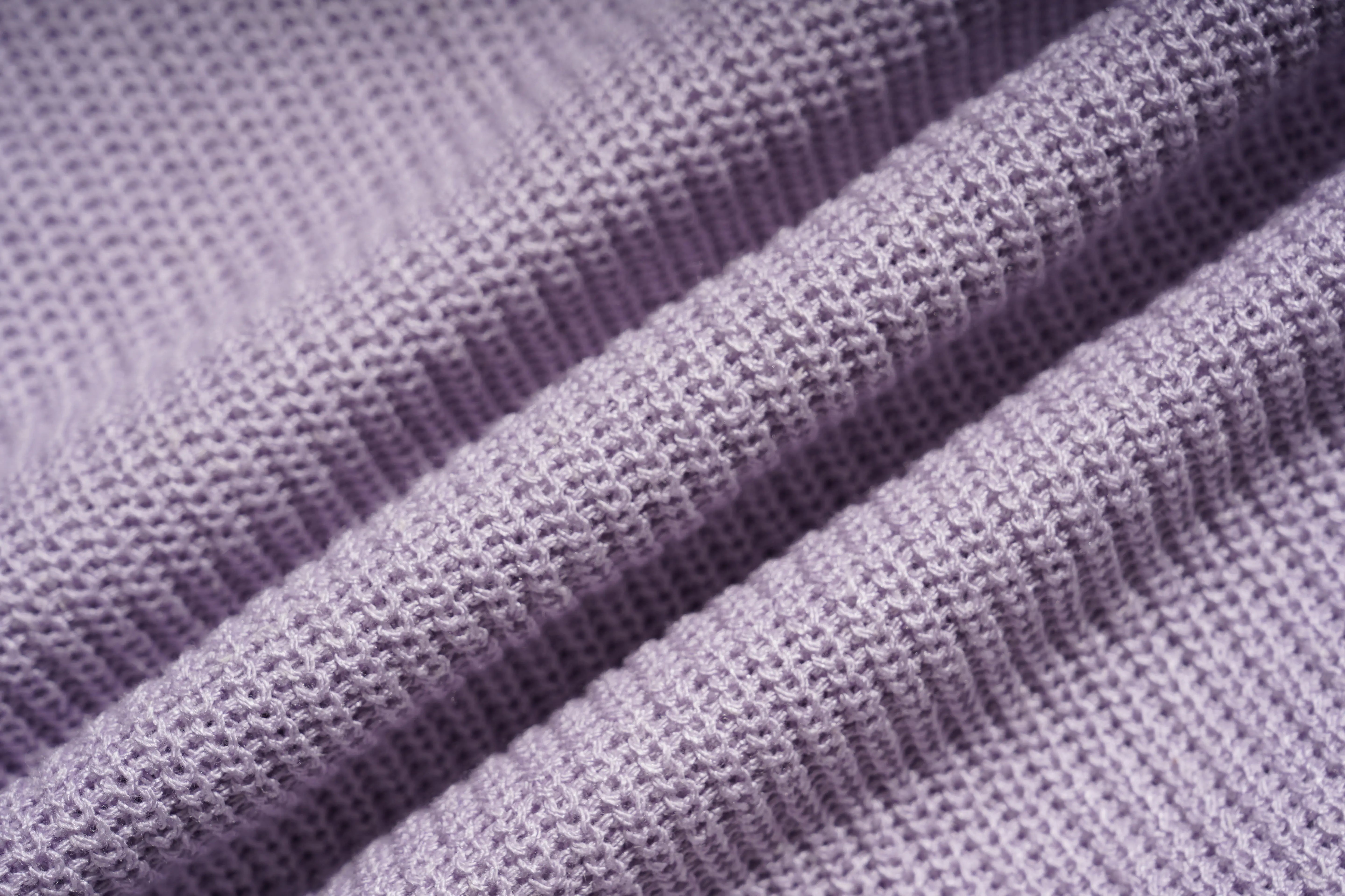 A close-up of a lavender purple knit fabric with a textured waffle or boucle pattern, shown in soft diagonal folds. TCH Rhinestone Butterfly Knit Twist Top