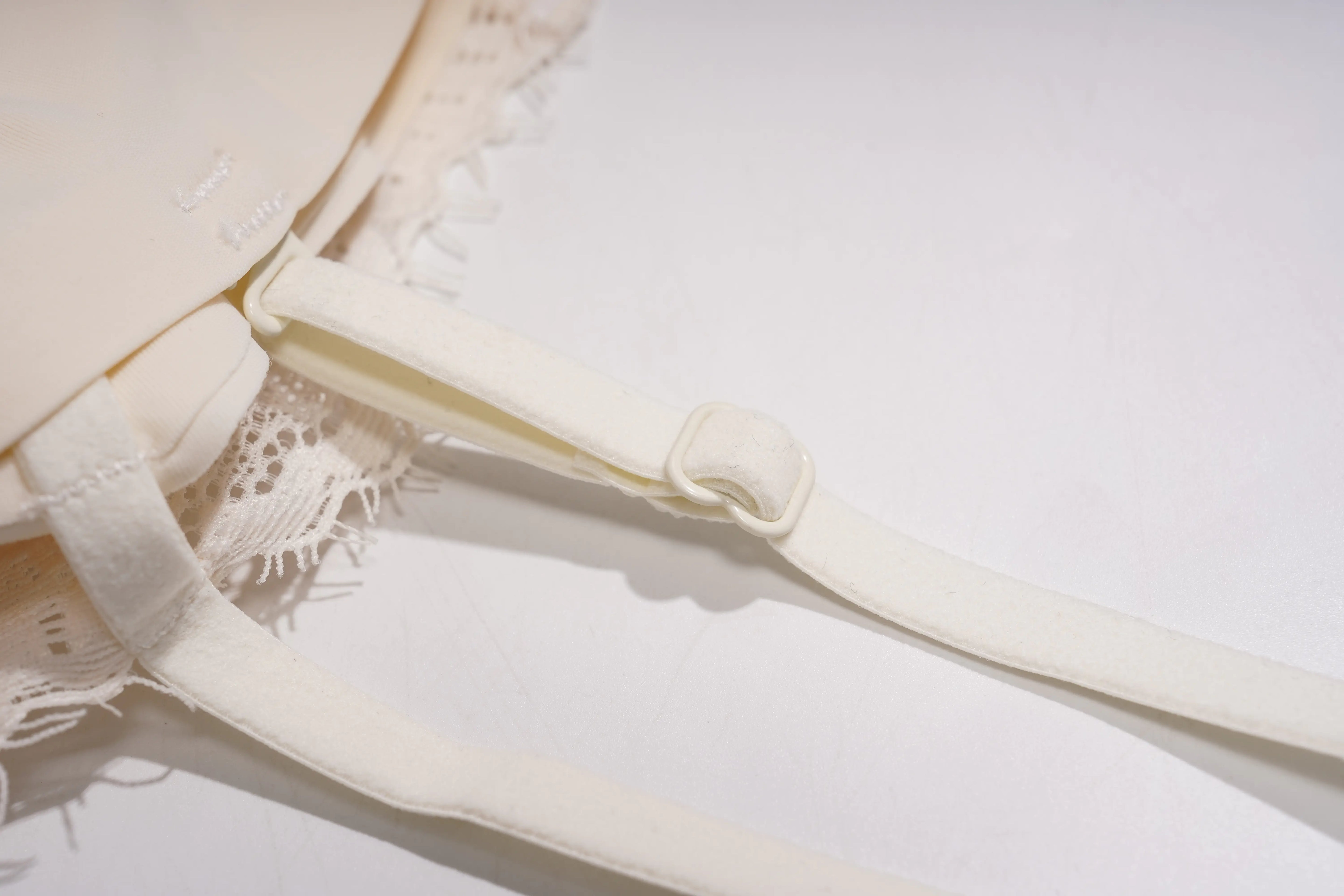 Close-up of a cream-colored bra strap and adjustable hook closure, with lace trim visible on the left side against a plain white background. TCH Rhinestone Butterfly Lace Cami Top