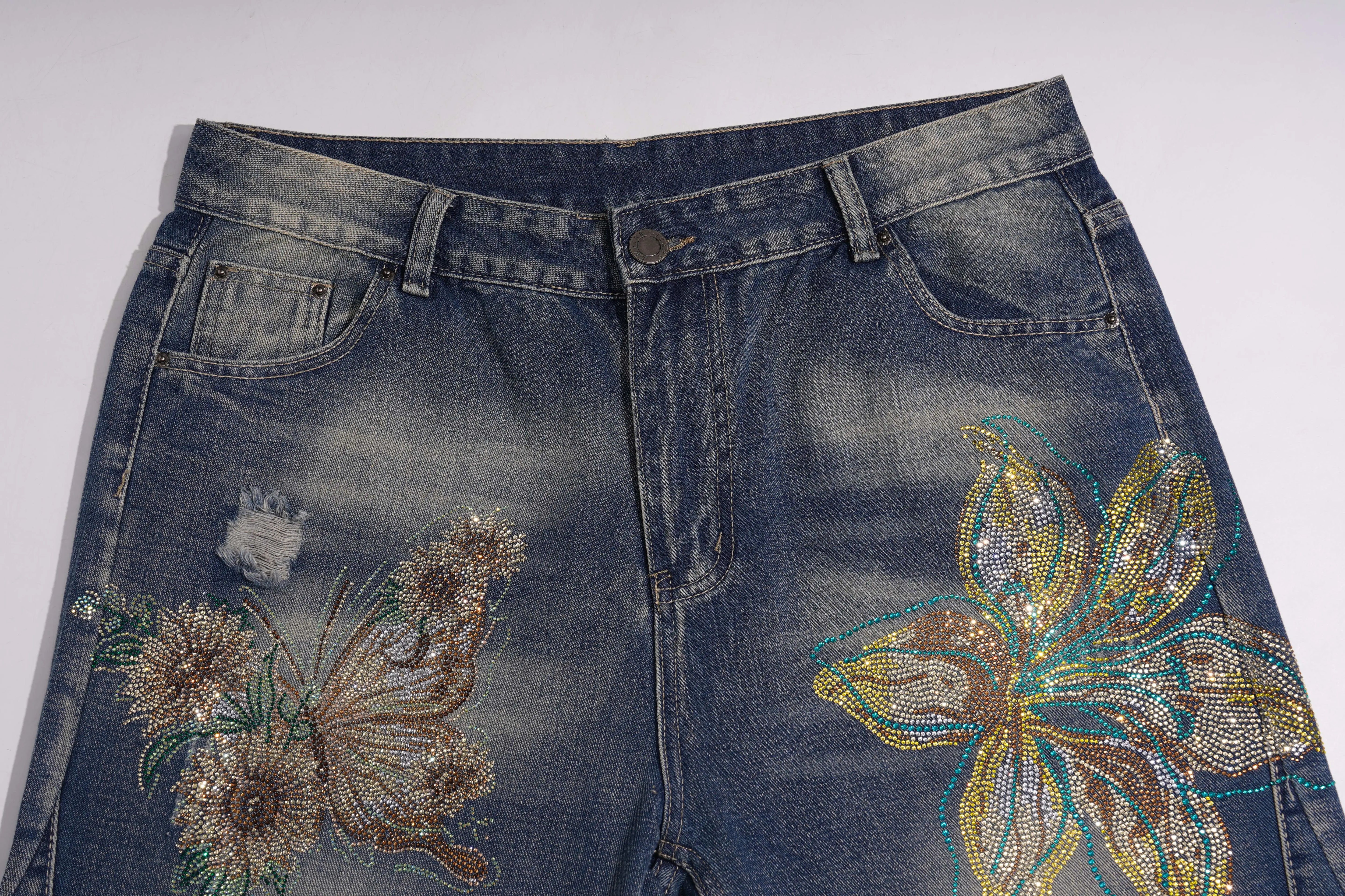 Blue jeans with floral and butterfly designs on a white background, TCH Rhinestone Butterfly & Lily Distressed Denim Jeans