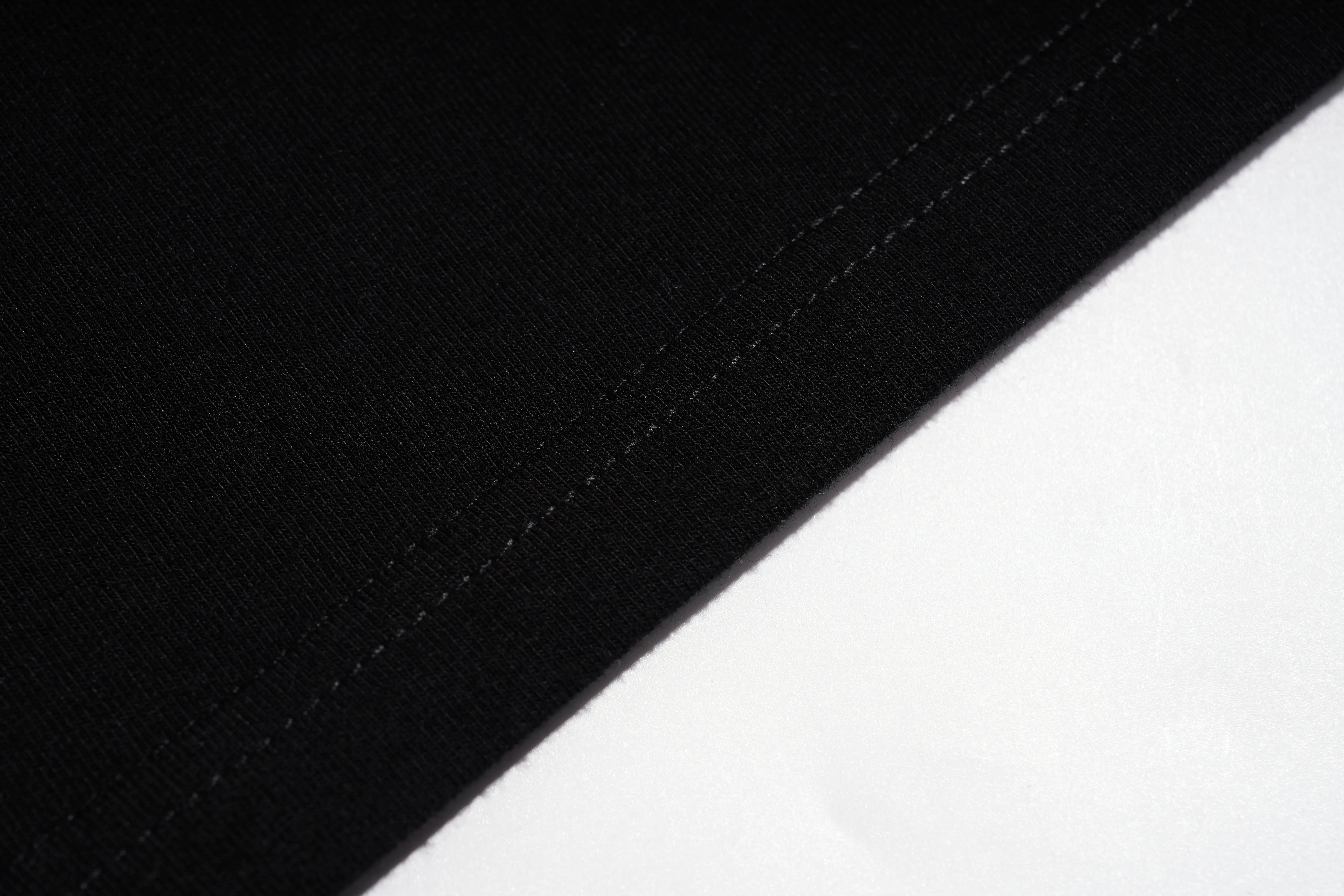 Close-up of a black fabric surface with a diagonal stitched edge meeting a white background. TCH Rhinestone Butterfly V-Neck Oversized Baseball T-Shirt