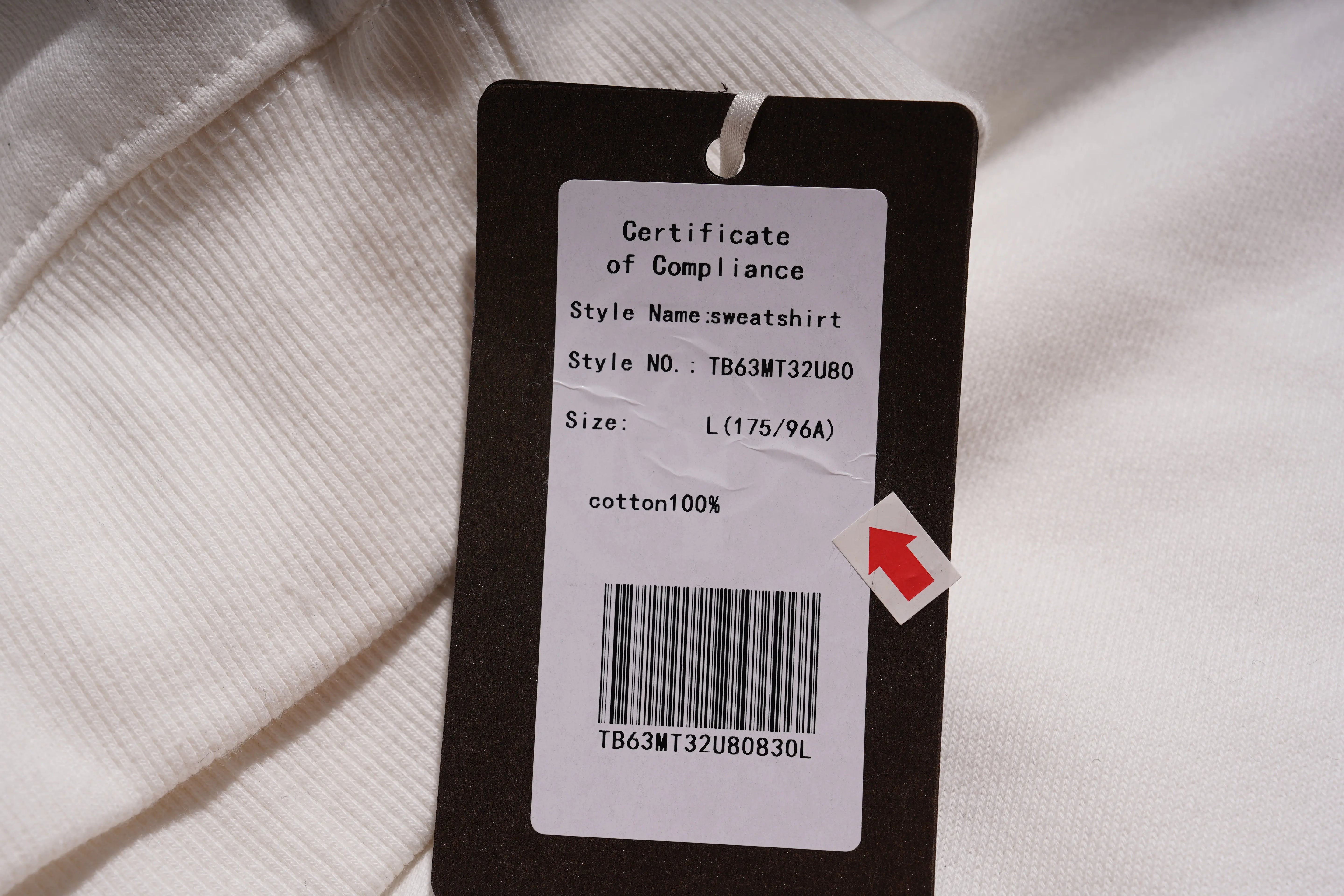 Clothing tag on a white sweatshirt with text and barcode details.