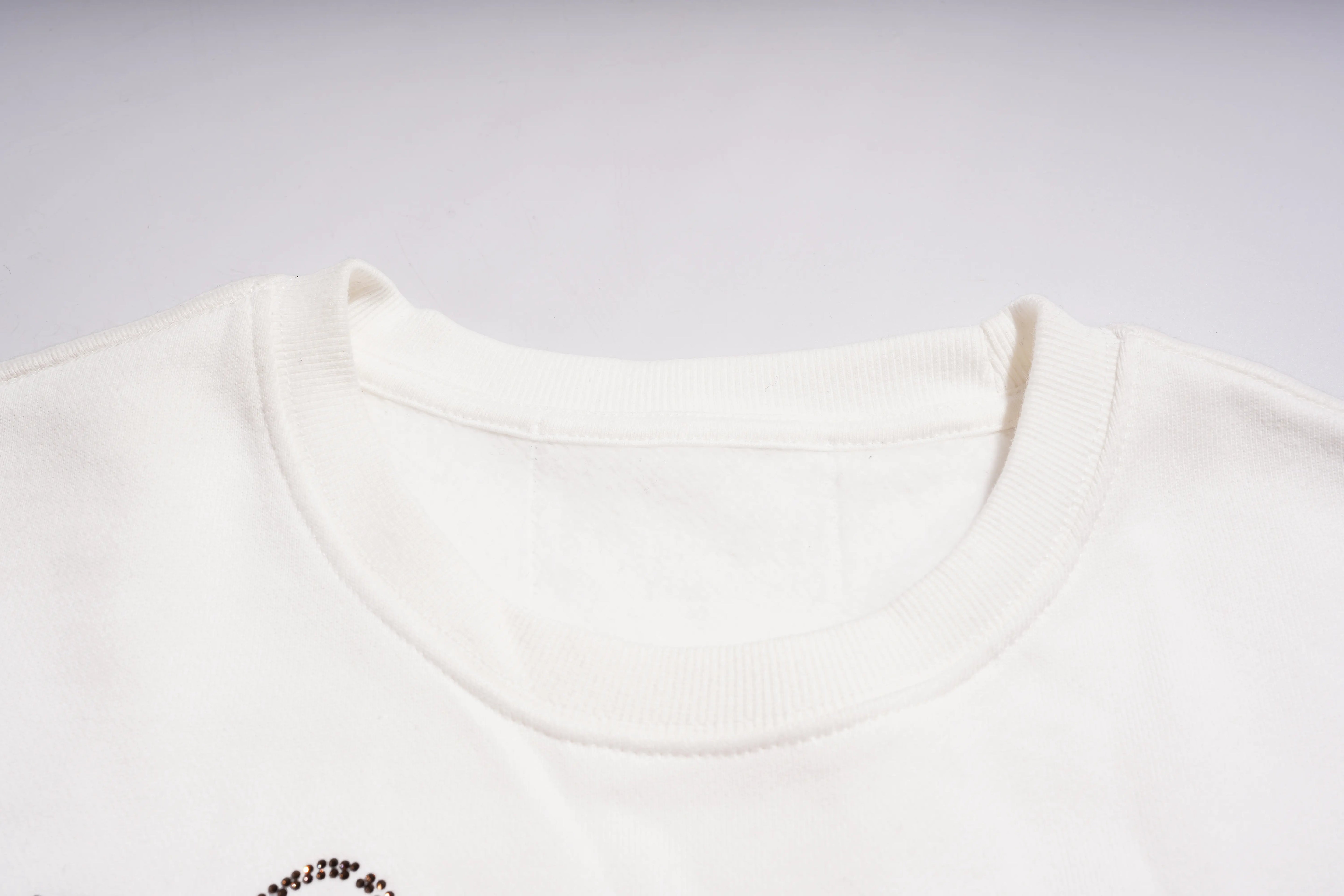 Close-up of a white t-shirt with a small logo on a light gray background