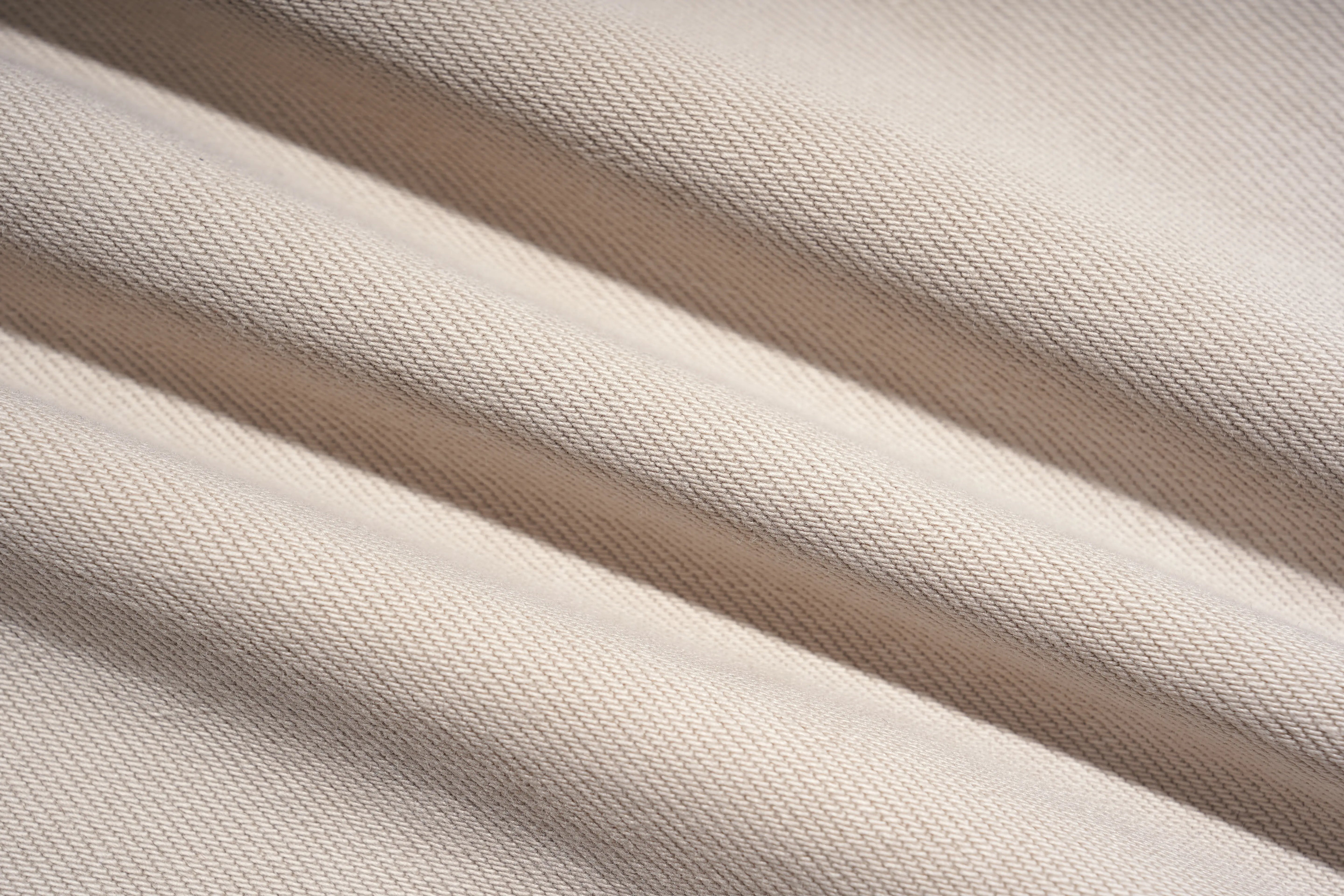 Close-up of a woven fabric with soft diagonal folds and shadows, showing a light warm neutral color. TCH Rhinestone Cherry Blossom Straight-Leg Jeans