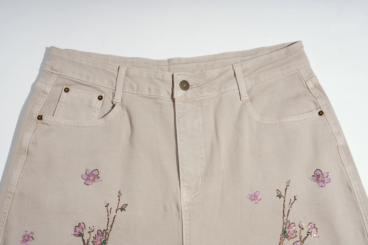 Beige denim skirt with pink floral embroidery and sequin accents on the front, shown against a plain white background. TCH Rhinestone Cherry Blossom Straight-Leg Jeans
